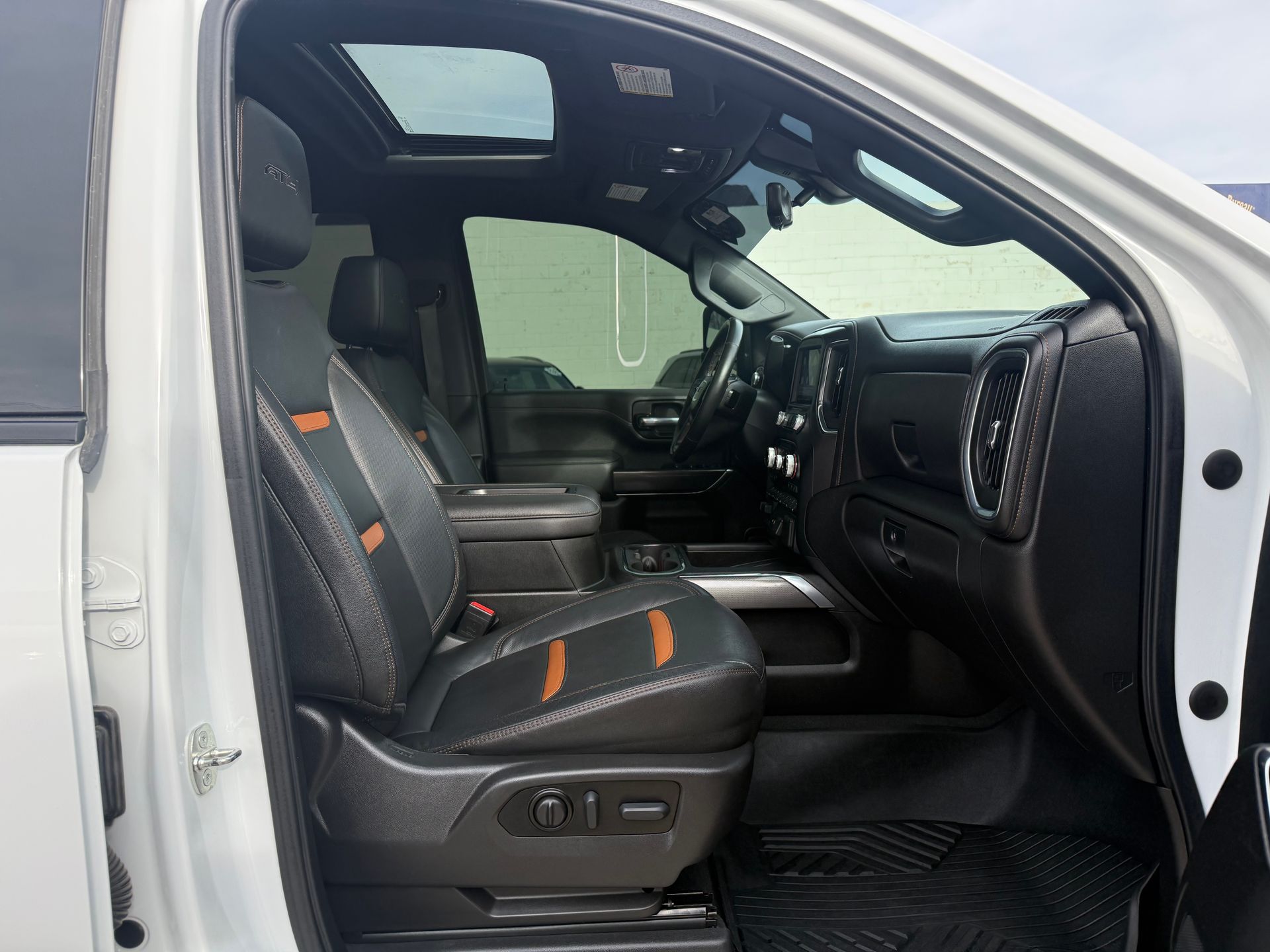 Interior of a white truck, with black and orange leather seats, sunroof, and dashboard visible.