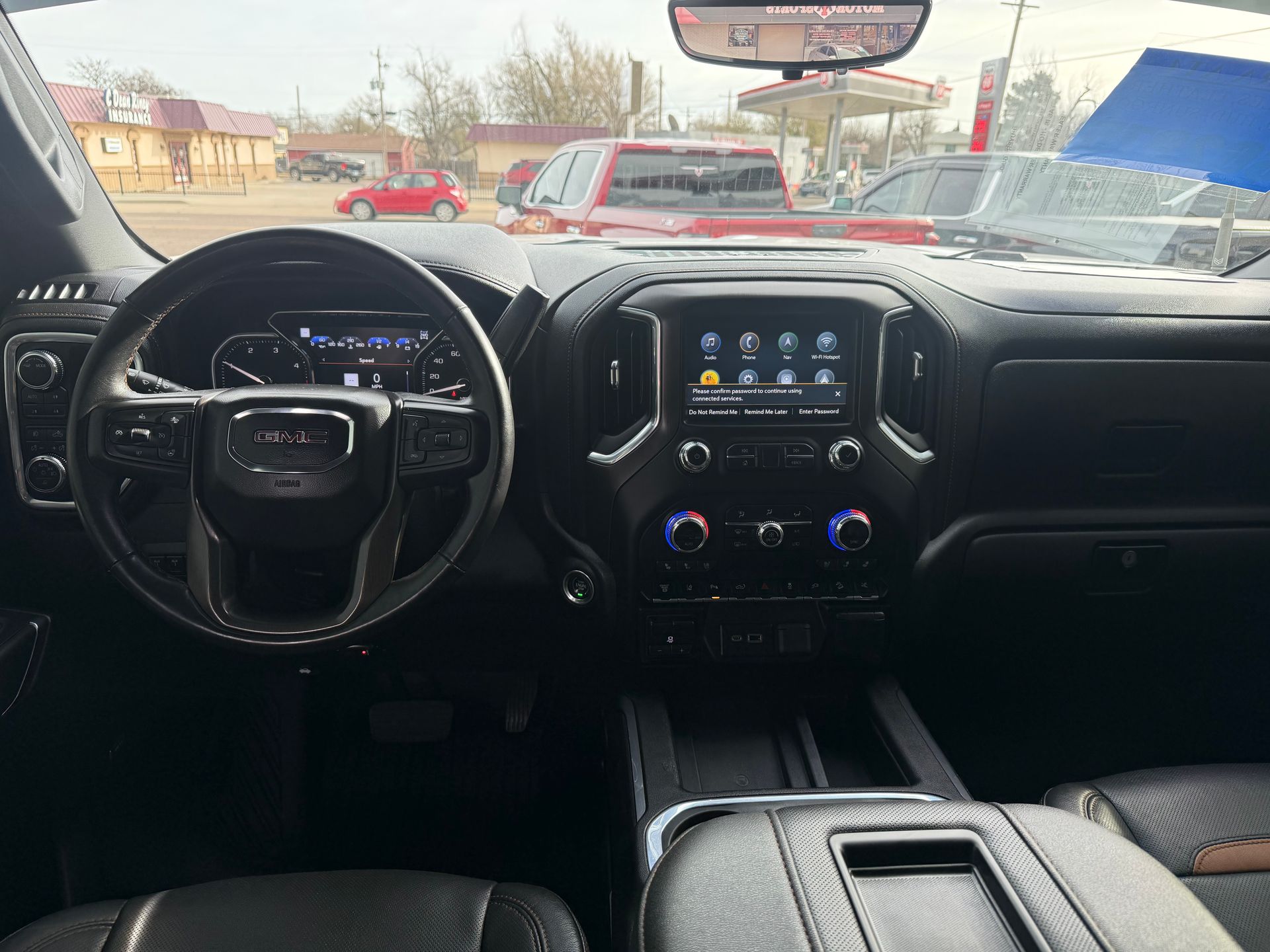 Interior view of a GMC Sierra truck. Black dashboard, steering wheel, and infotainment screen.