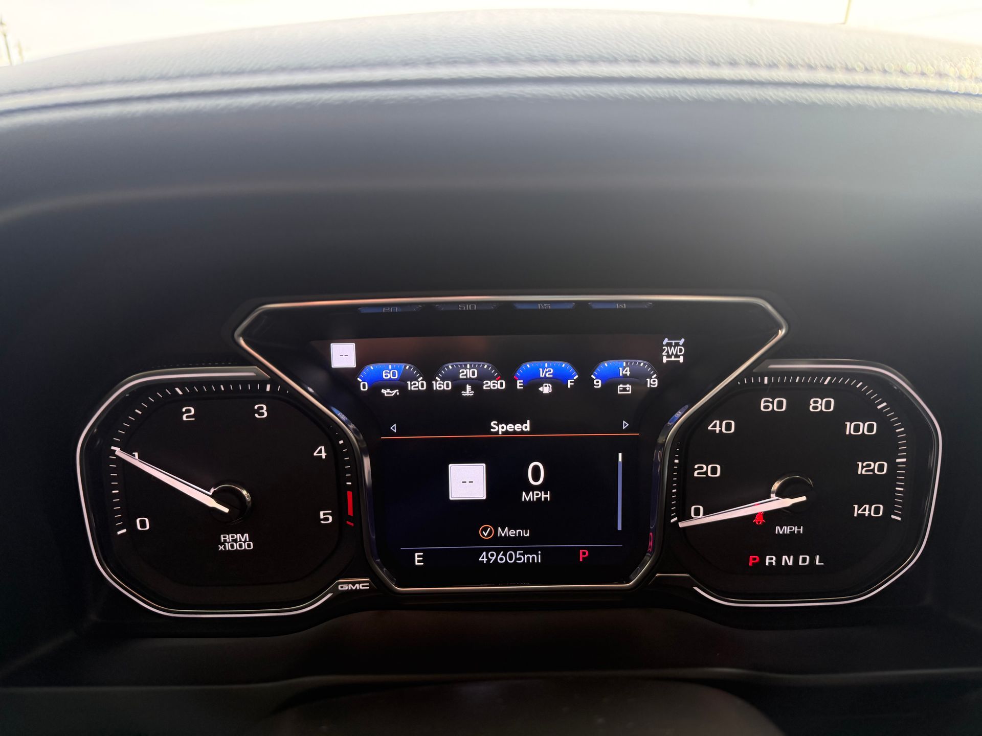Dashboard of a vehicle, displaying speedometer, gauges, and digital information; vehicle is parked.