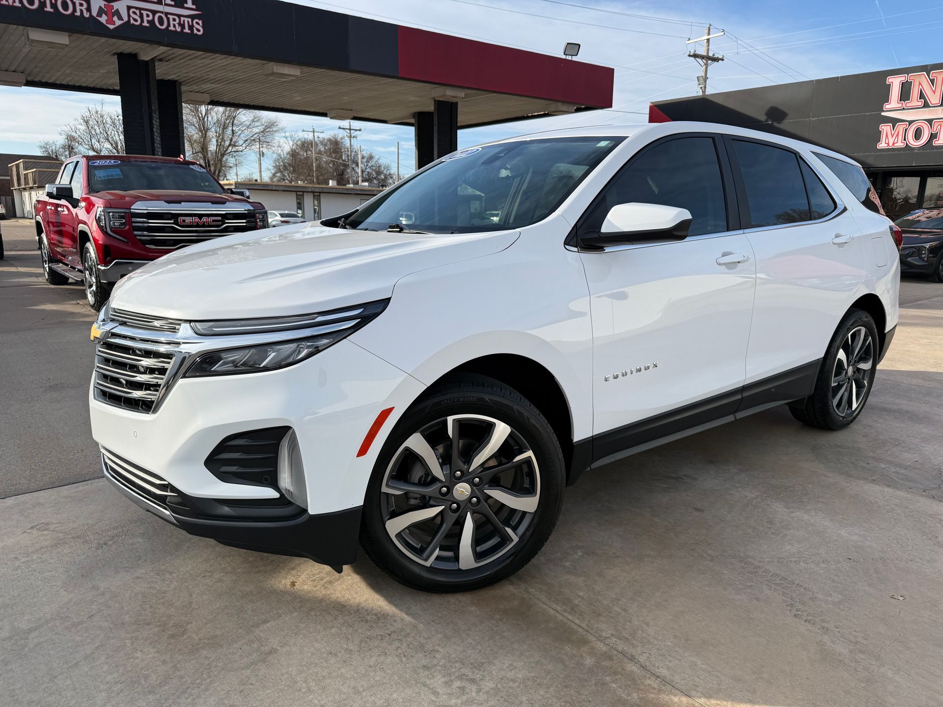 Blue Volkswagen Taos SUV parked in front of a car dealership on a sunny day.