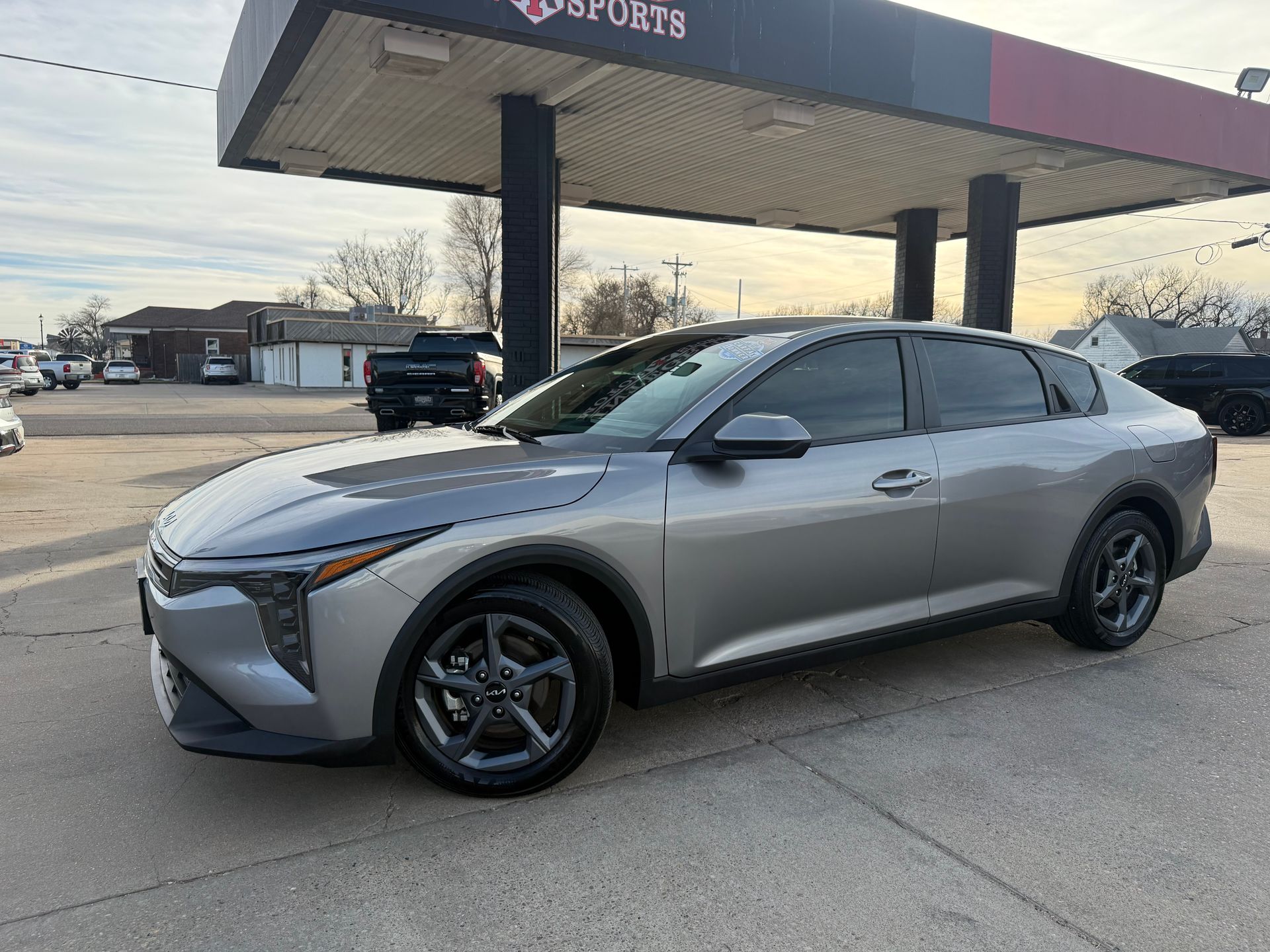 Red Nissan Altima sedan parked at a car dealership on a sunny day.