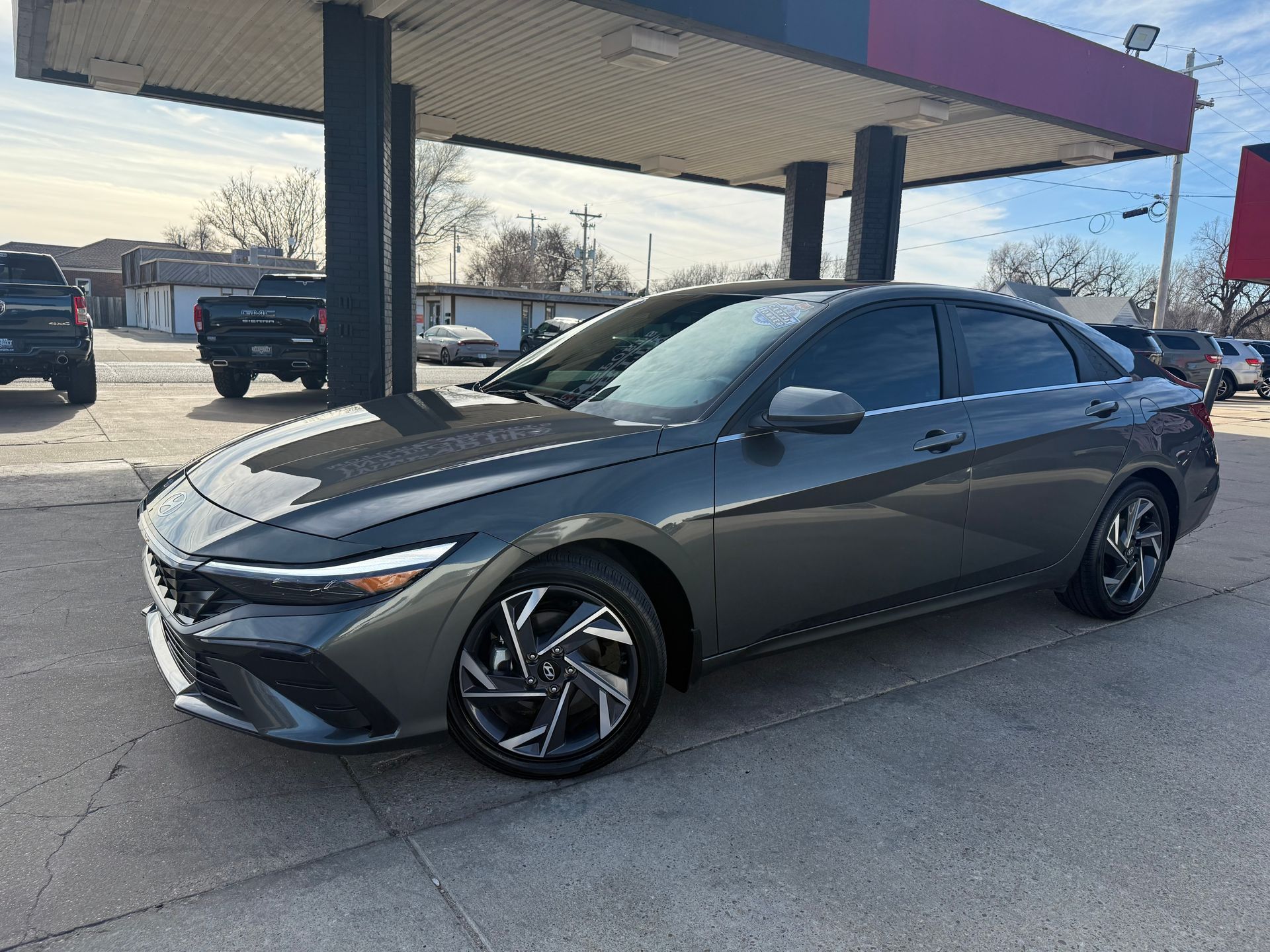 Red Nissan Altima sedan parked at a car dealership on a sunny day.