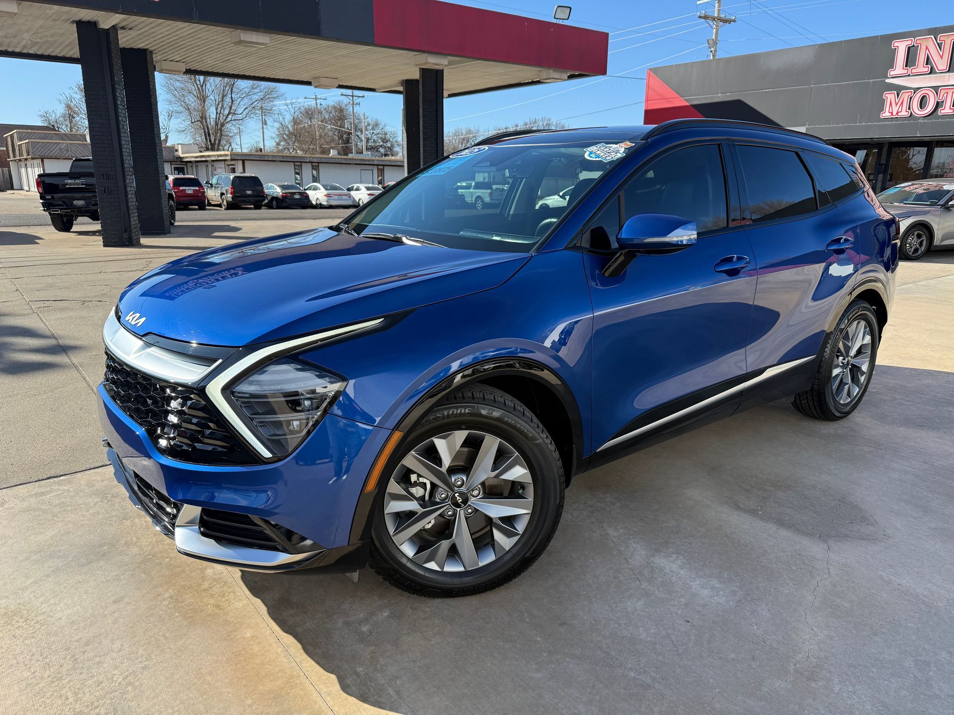 Black Buick Enclave SUV parked on a sunny day in front of an auto shop.