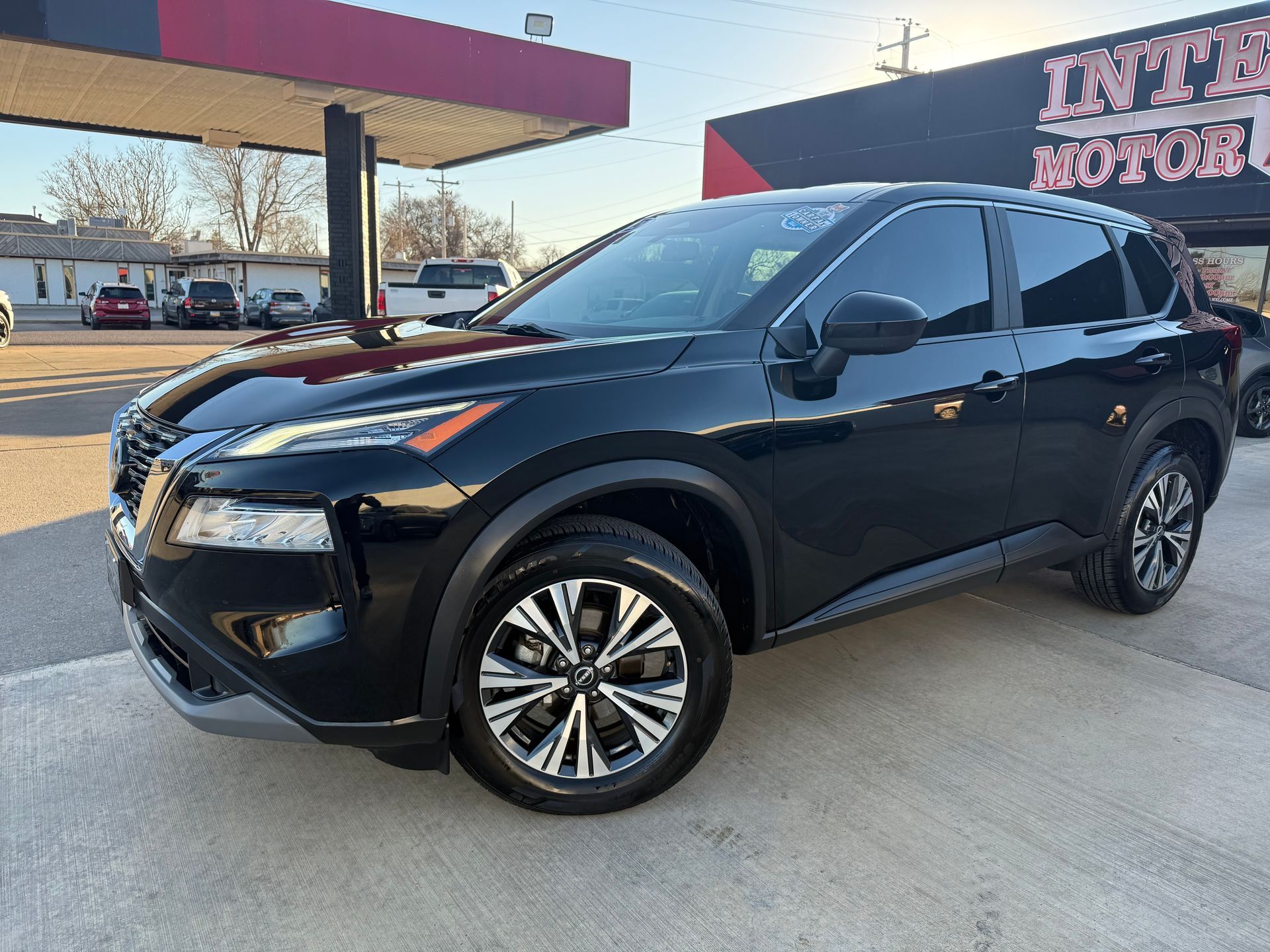 Black Buick Enclave SUV parked on a sunny day in front of an auto shop.