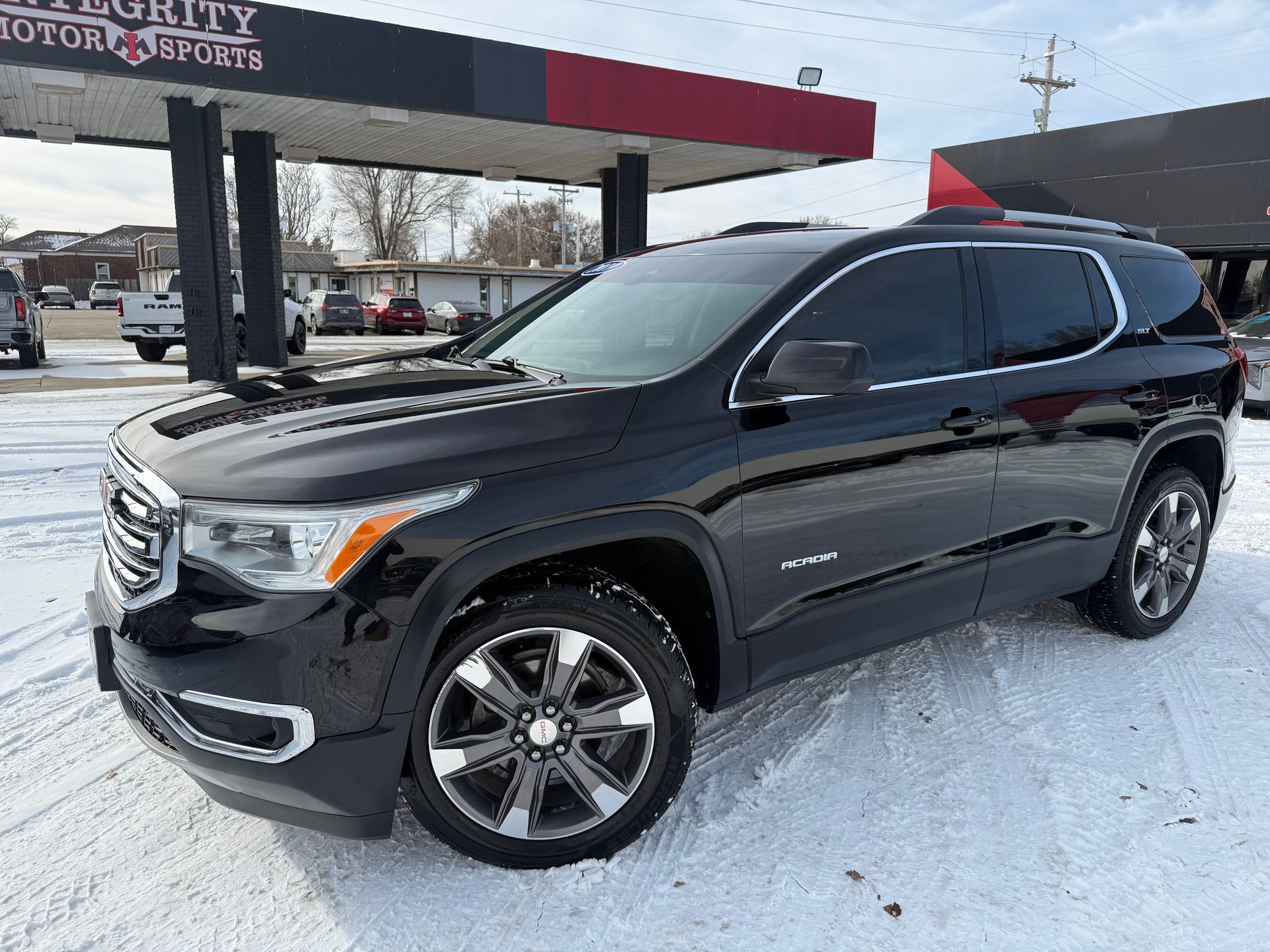 Black Buick Enclave SUV parked on a sunny day in front of an auto shop.