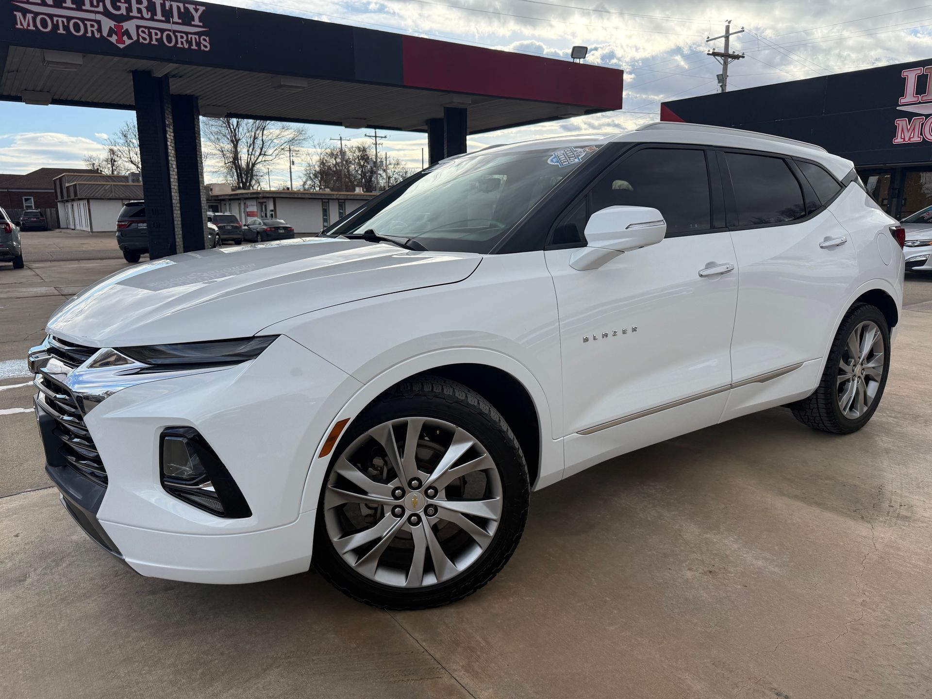 Black Buick Enclave SUV parked on a sunny day in front of an auto shop.