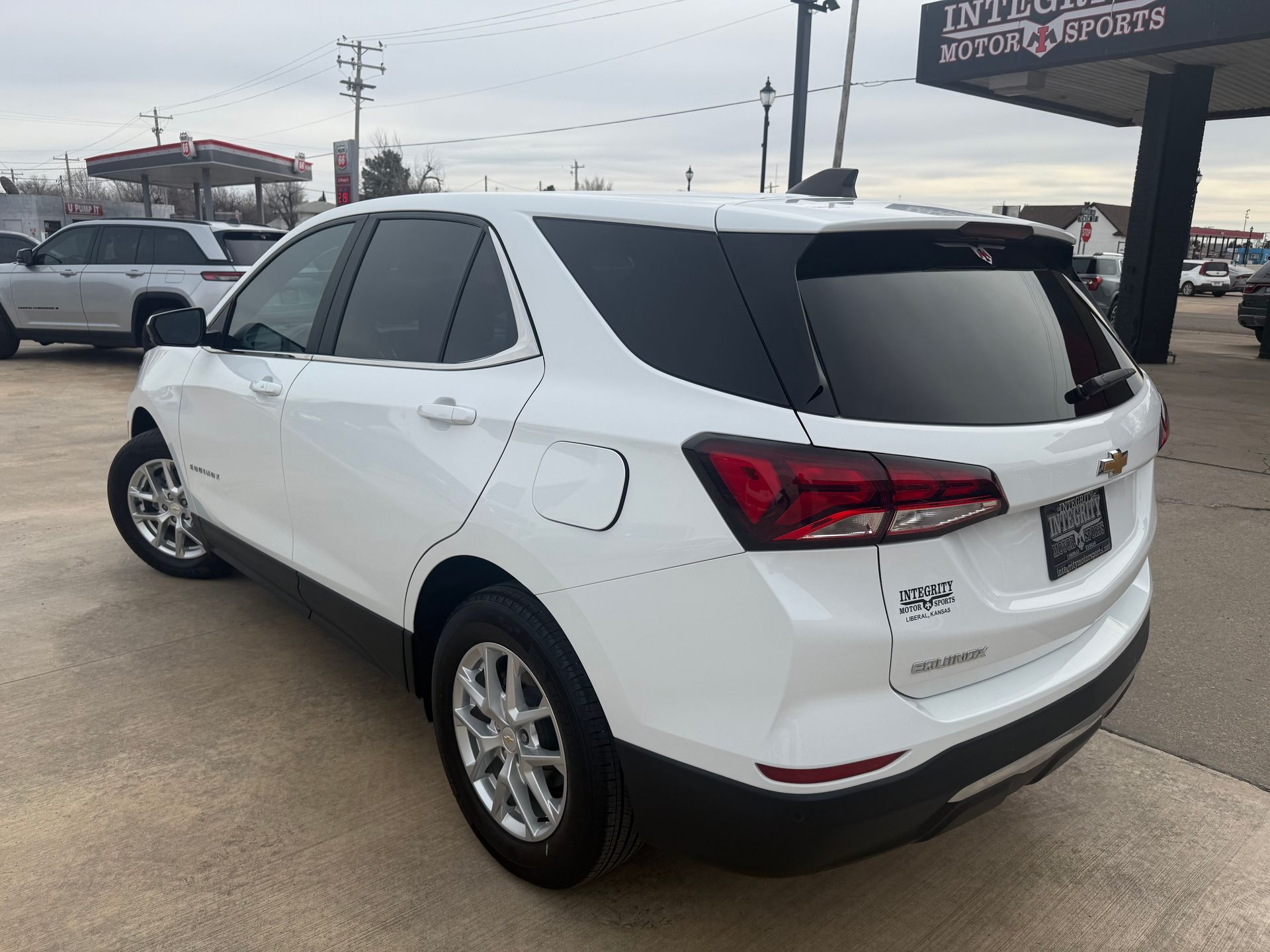 White Chevy Equinox SUV, parked outdoors on a cloudy day, dealership background.