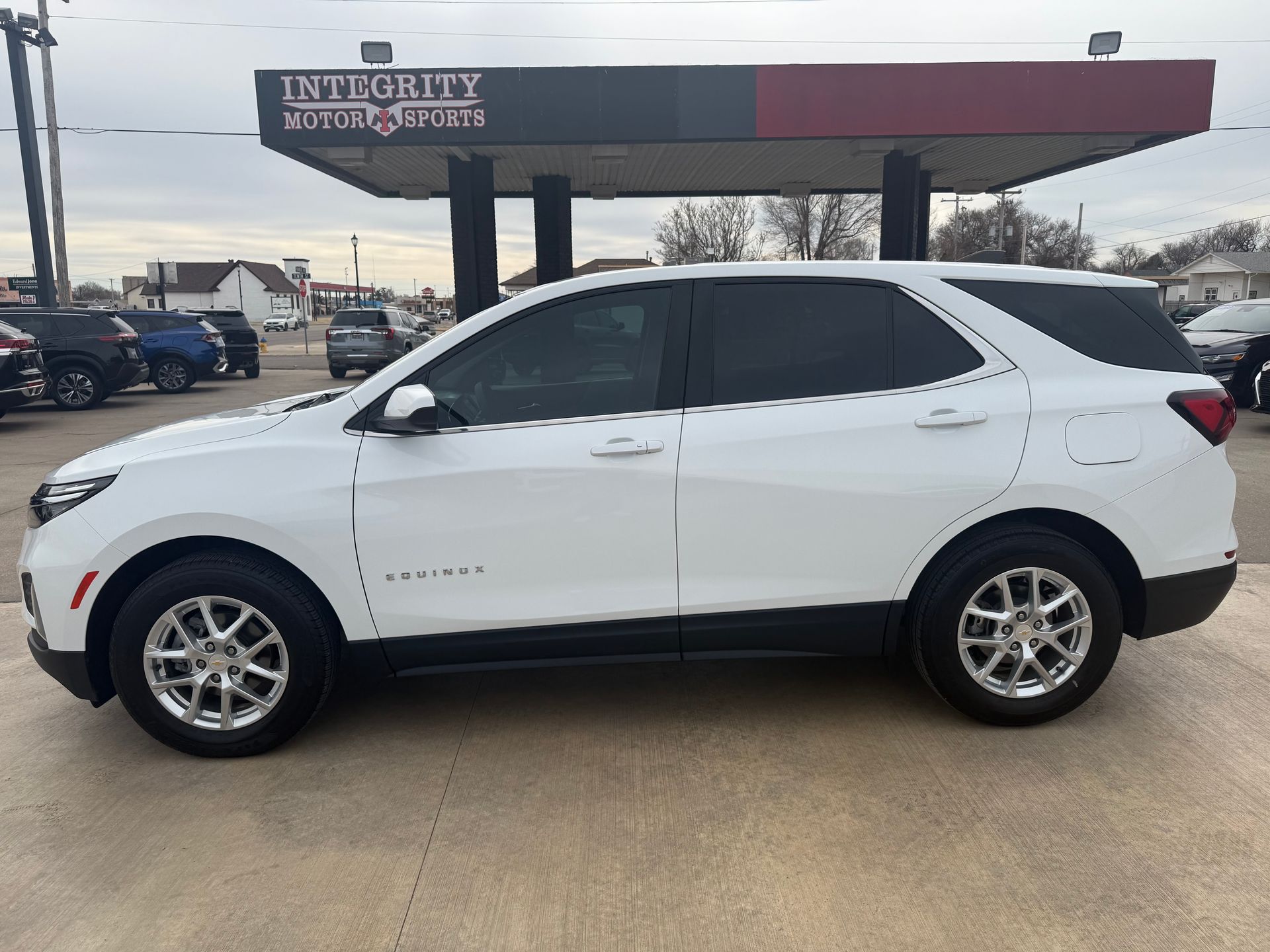 White SUV parked outside a car dealership under a sign that reads 