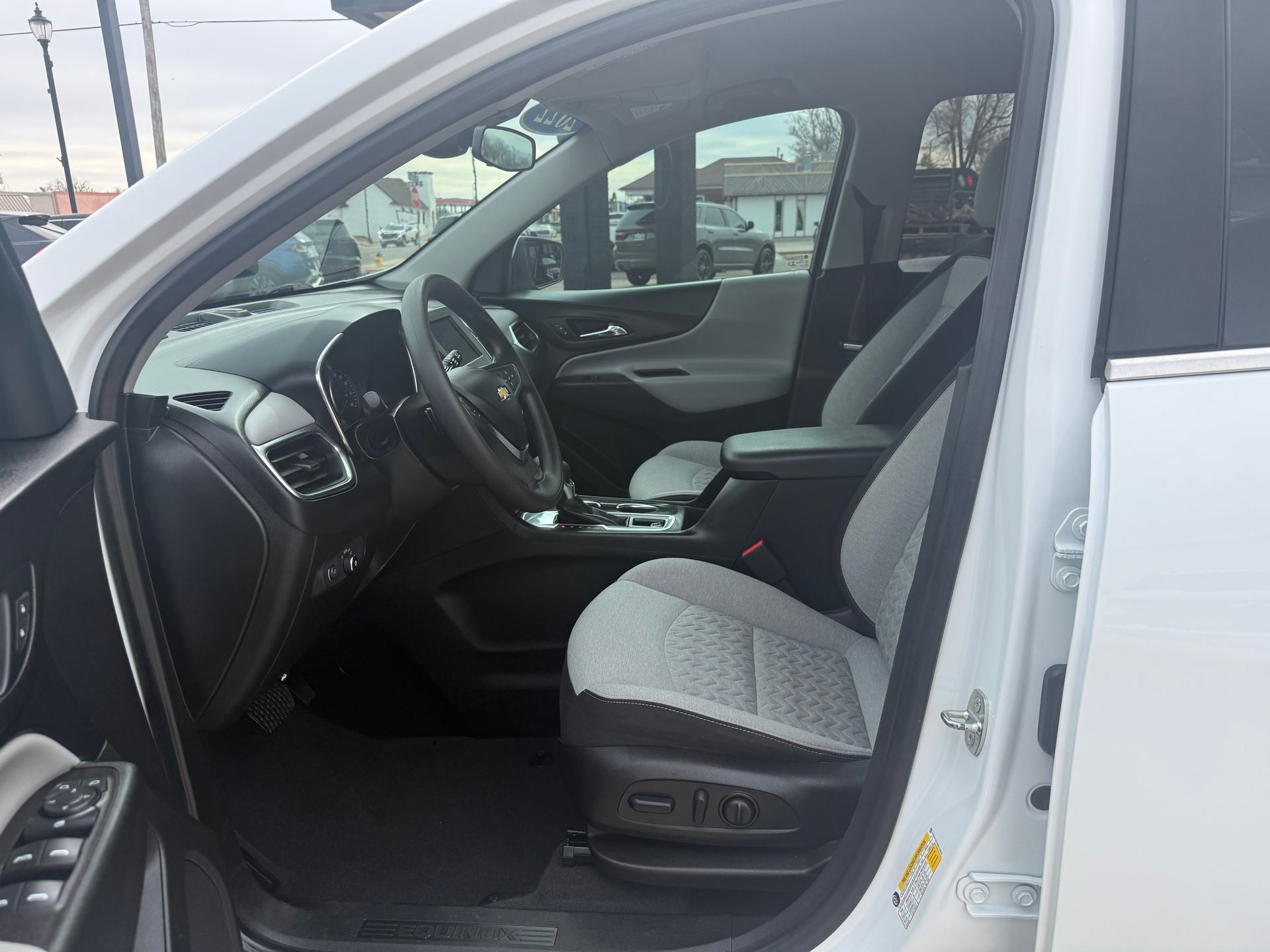 White car interior with gray and black seats, steering wheel, and dashboard.