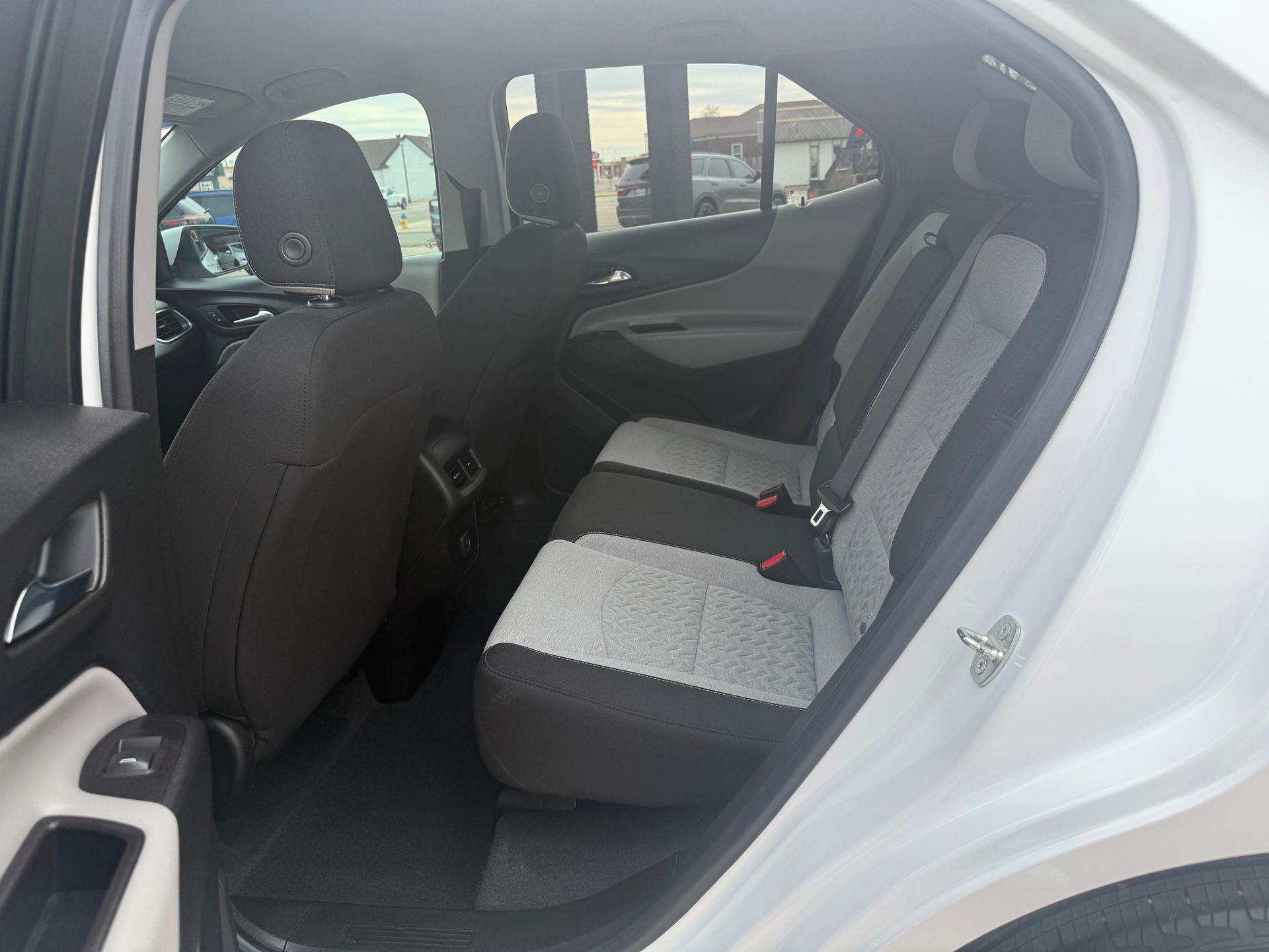 Interior view of a white SUV with gray and black patterned rear seats and dark door panels.