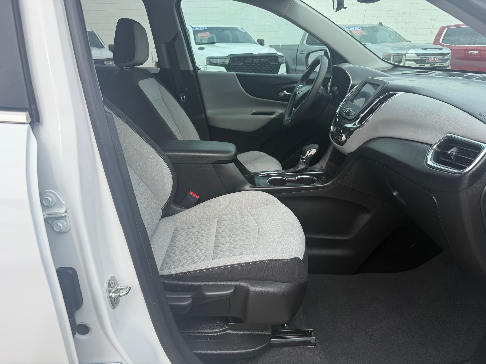 Interior of a car with a white and black seat, dashboard, and steering wheel.