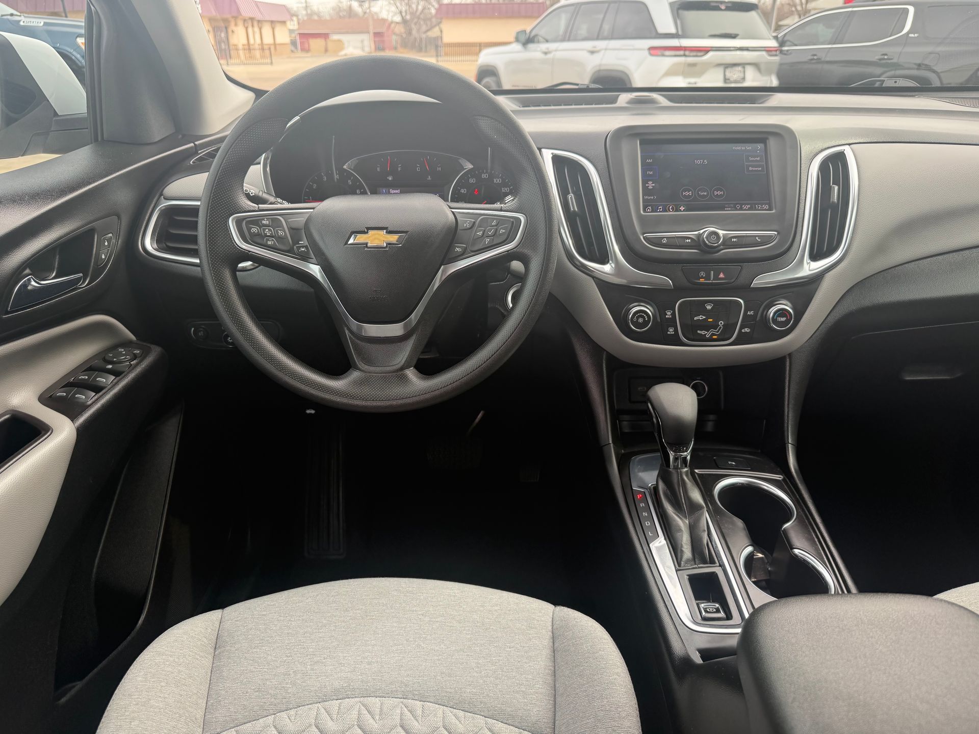 Interior view of a black and gray Chevrolet Equinox dashboard, steering wheel, and console.