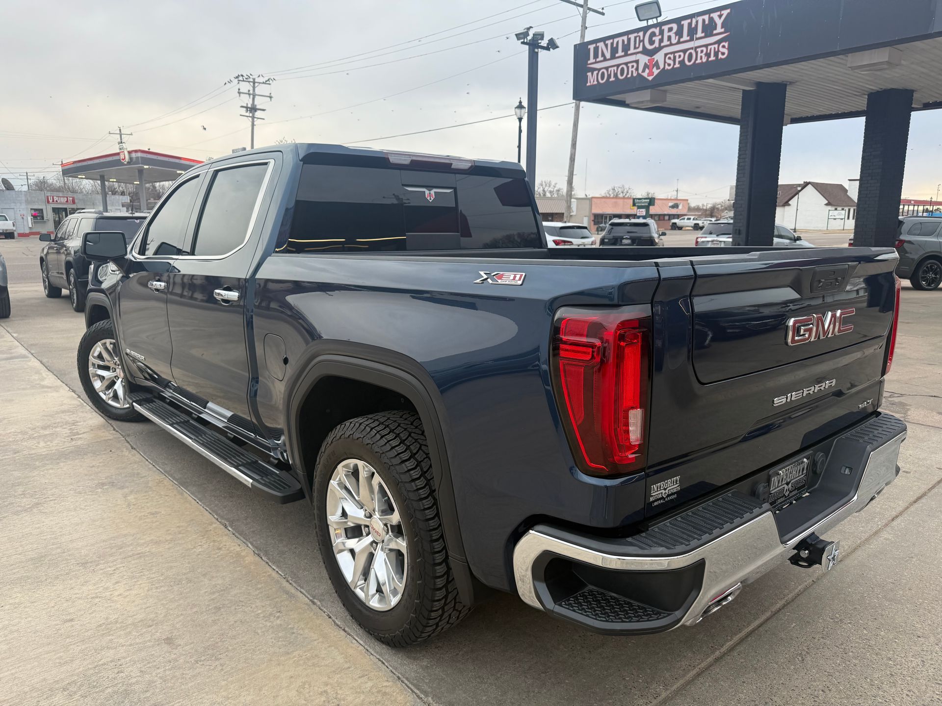 Dark blue GMC Sierra pickup truck parked at a dealership, with chrome accents and a black bed cover.