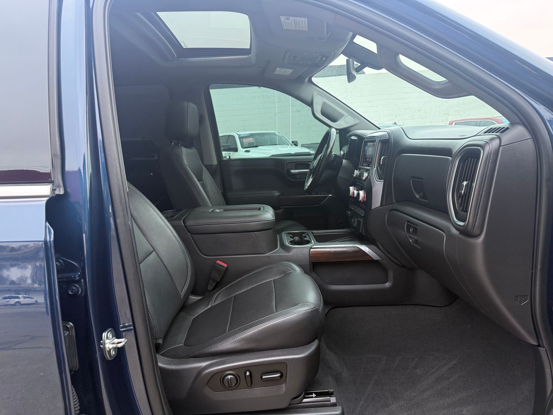 Interior view of a blue truck with black leather seats, dashboard, and a sunroof.