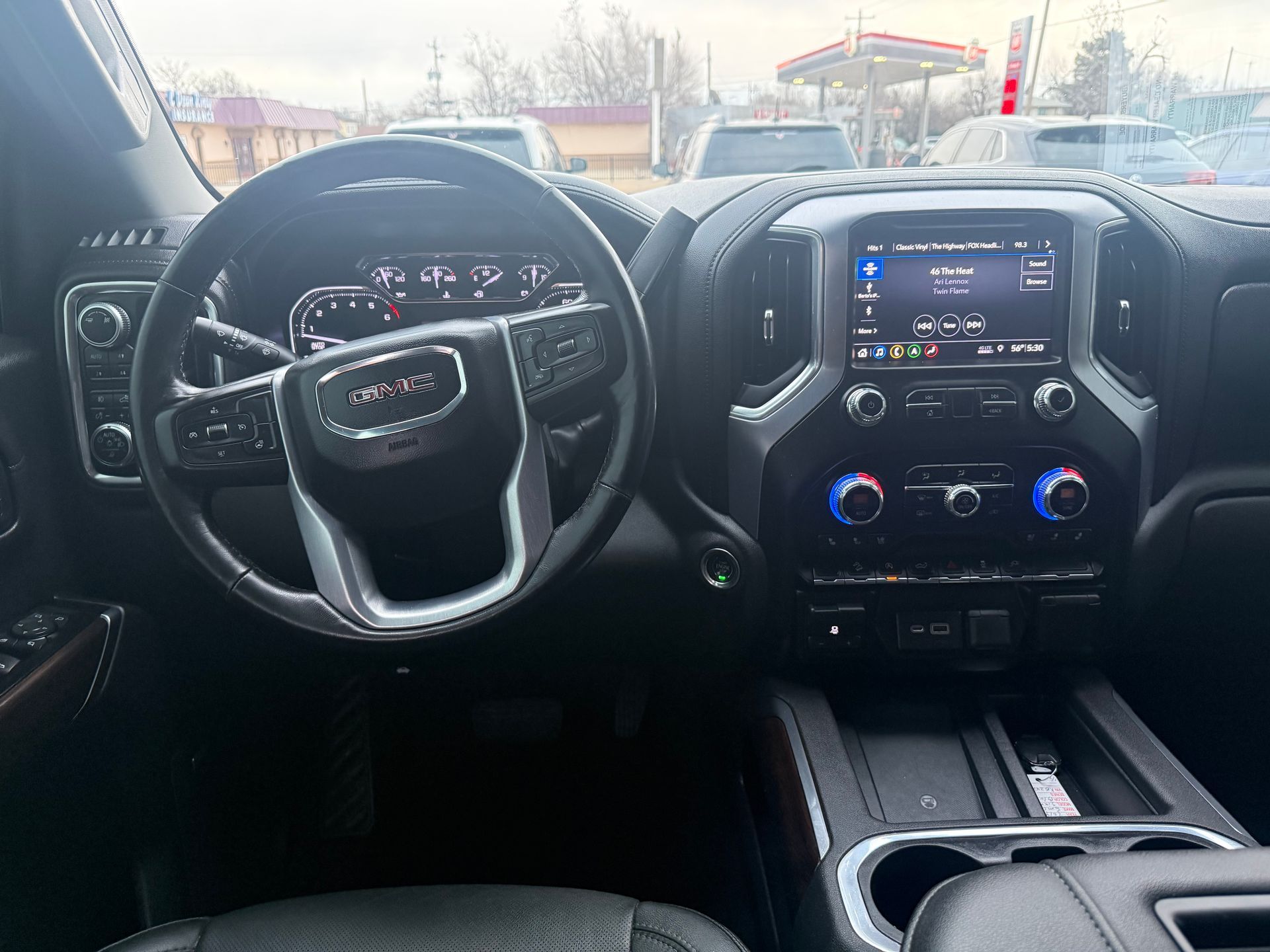 Interior of a GMC truck dashboard, including steering wheel, infotainment screen, and controls.