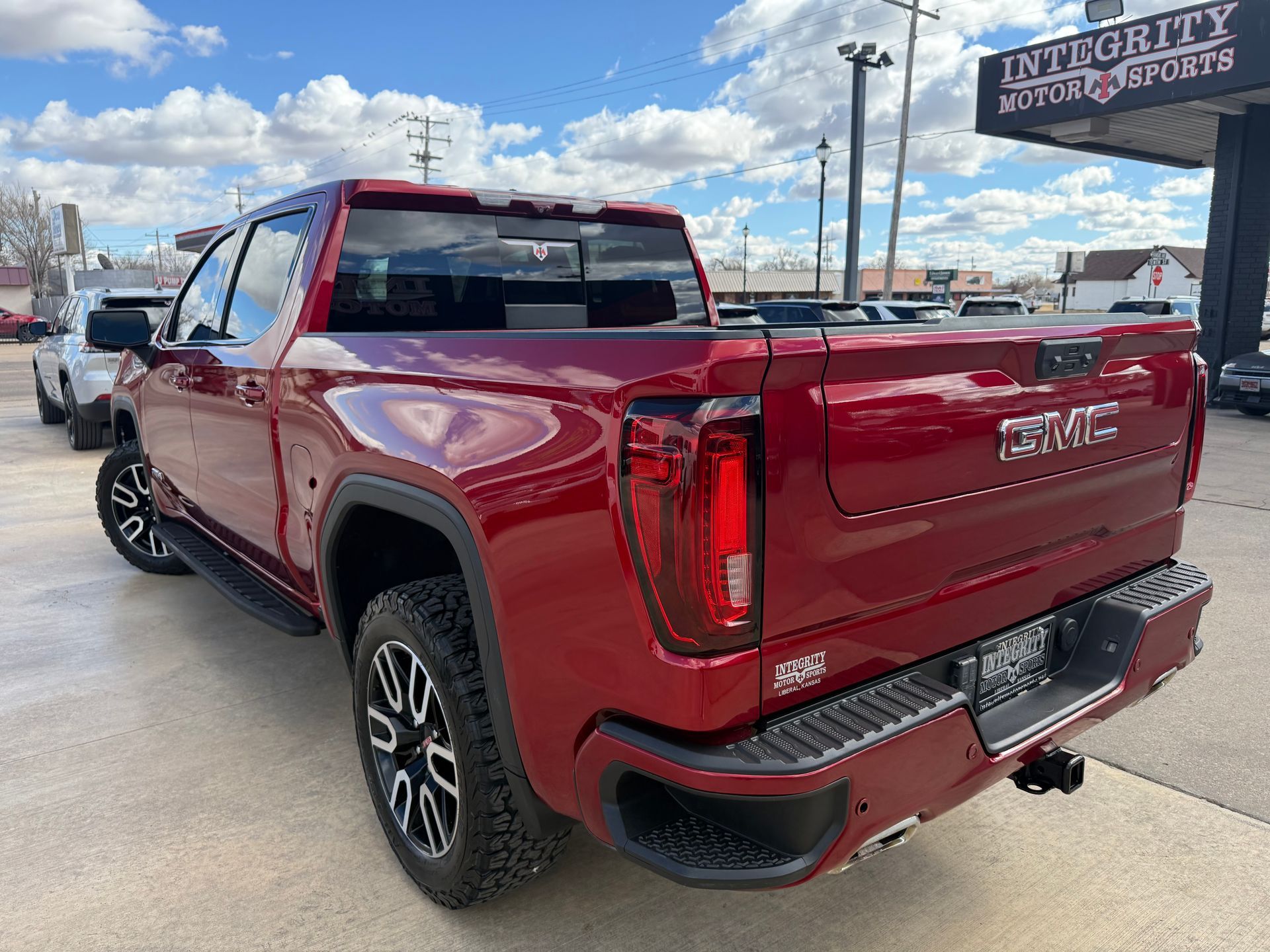 Red GMC pickup truck parked outside a dealership on a sunny day.