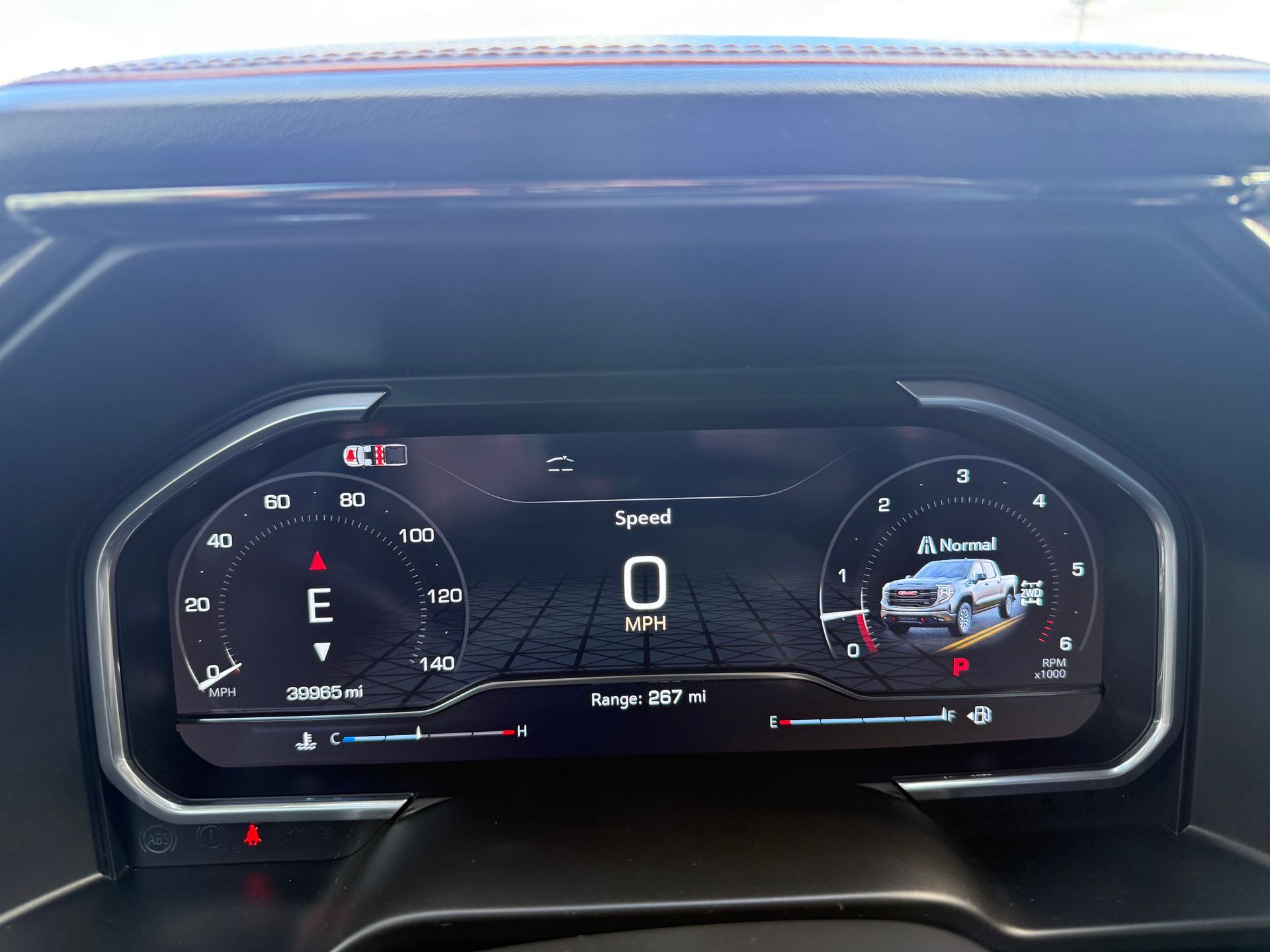Dashboard of a car showing speedometer at zero mph, fuel gauge, and vehicle silhouette. Red and black color scheme.