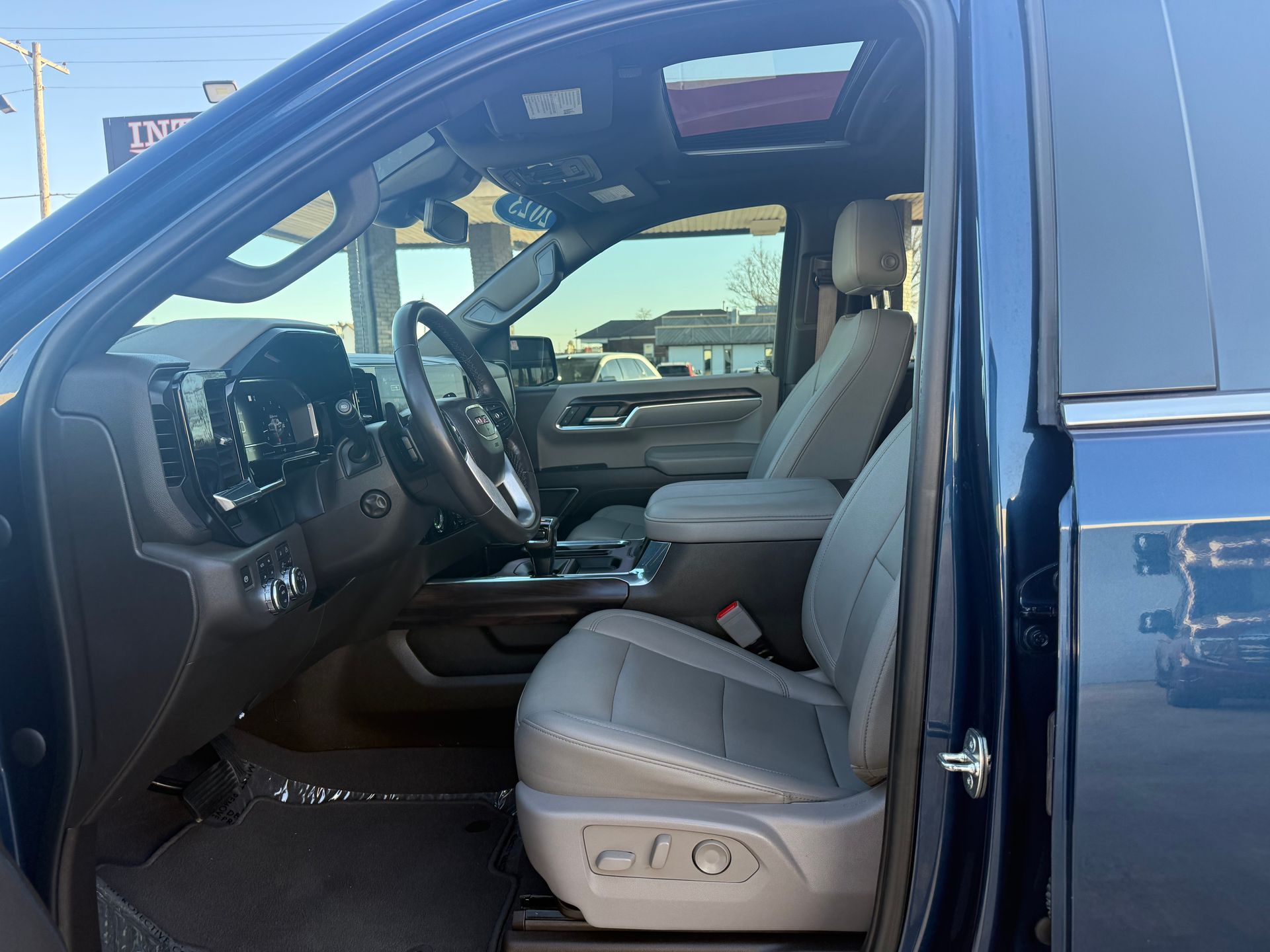 Blue truck interior with gray leather seats, open door. Sunroof visible.