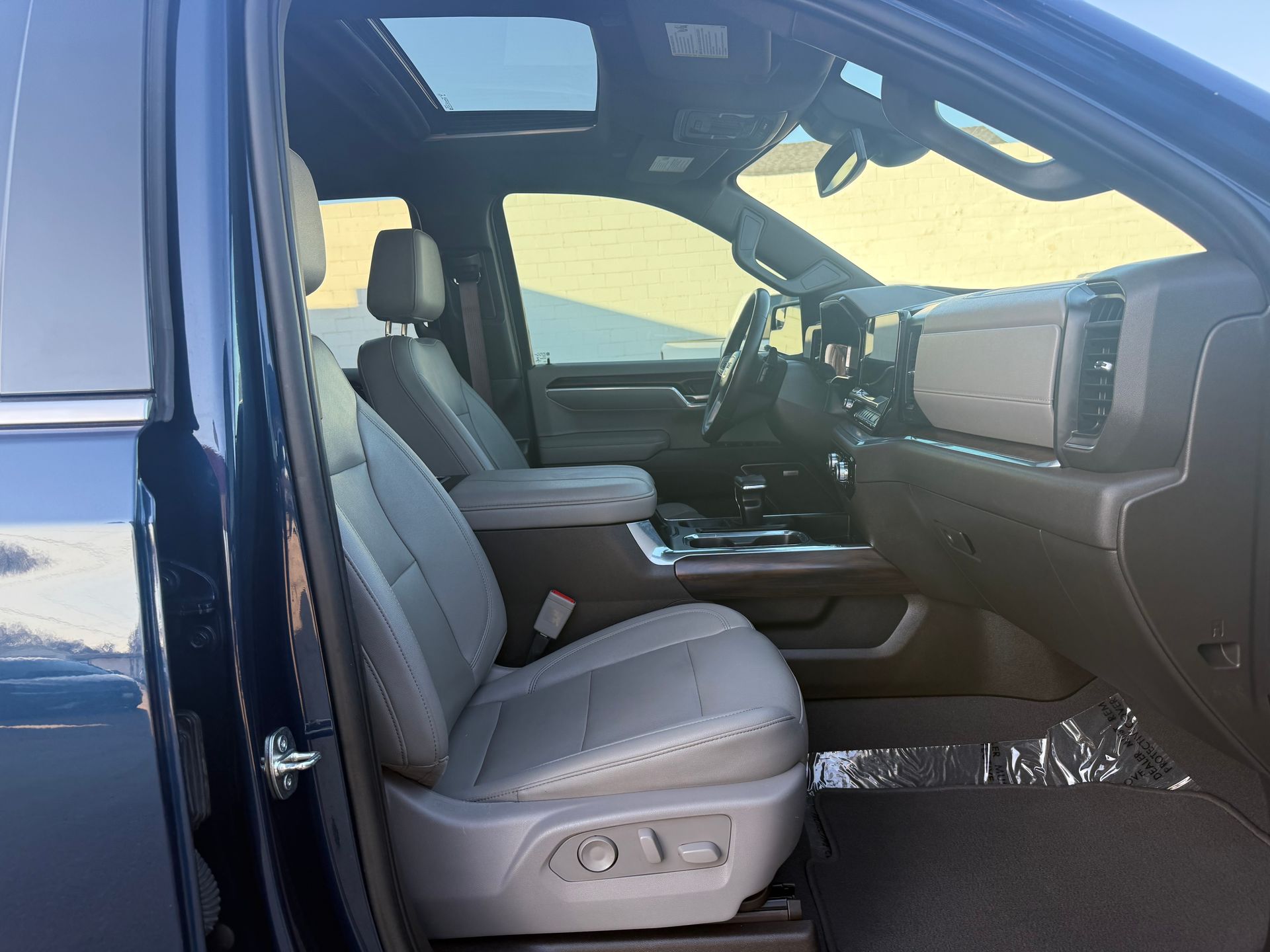 Interior of a blue truck with gray leather seats, sunroof, and dashboard visible.