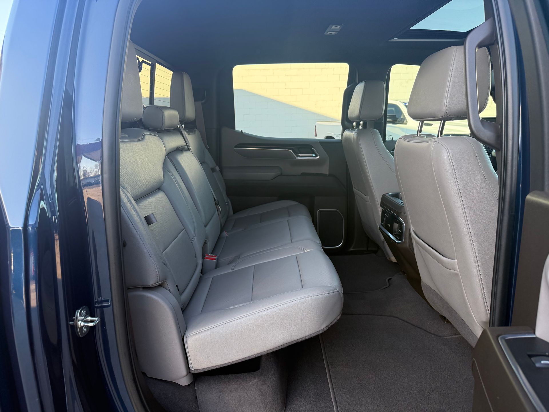 Interior view of a blue pickup truck backseat with gray leather seats and a sunroof.