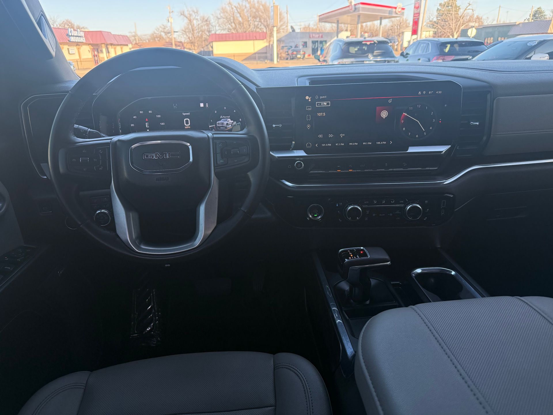Dashboard of a GMC pickup truck, steering wheel, infotainment screen, and console visible.