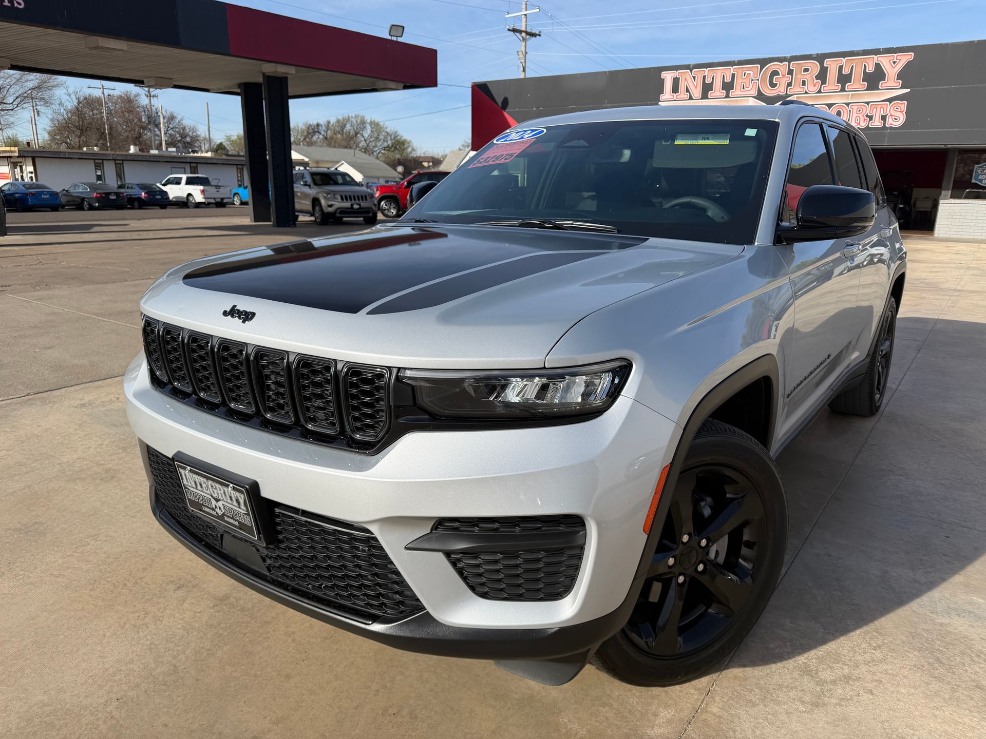 Black Buick Enclave SUV parked on a sunny day in front of an auto shop.