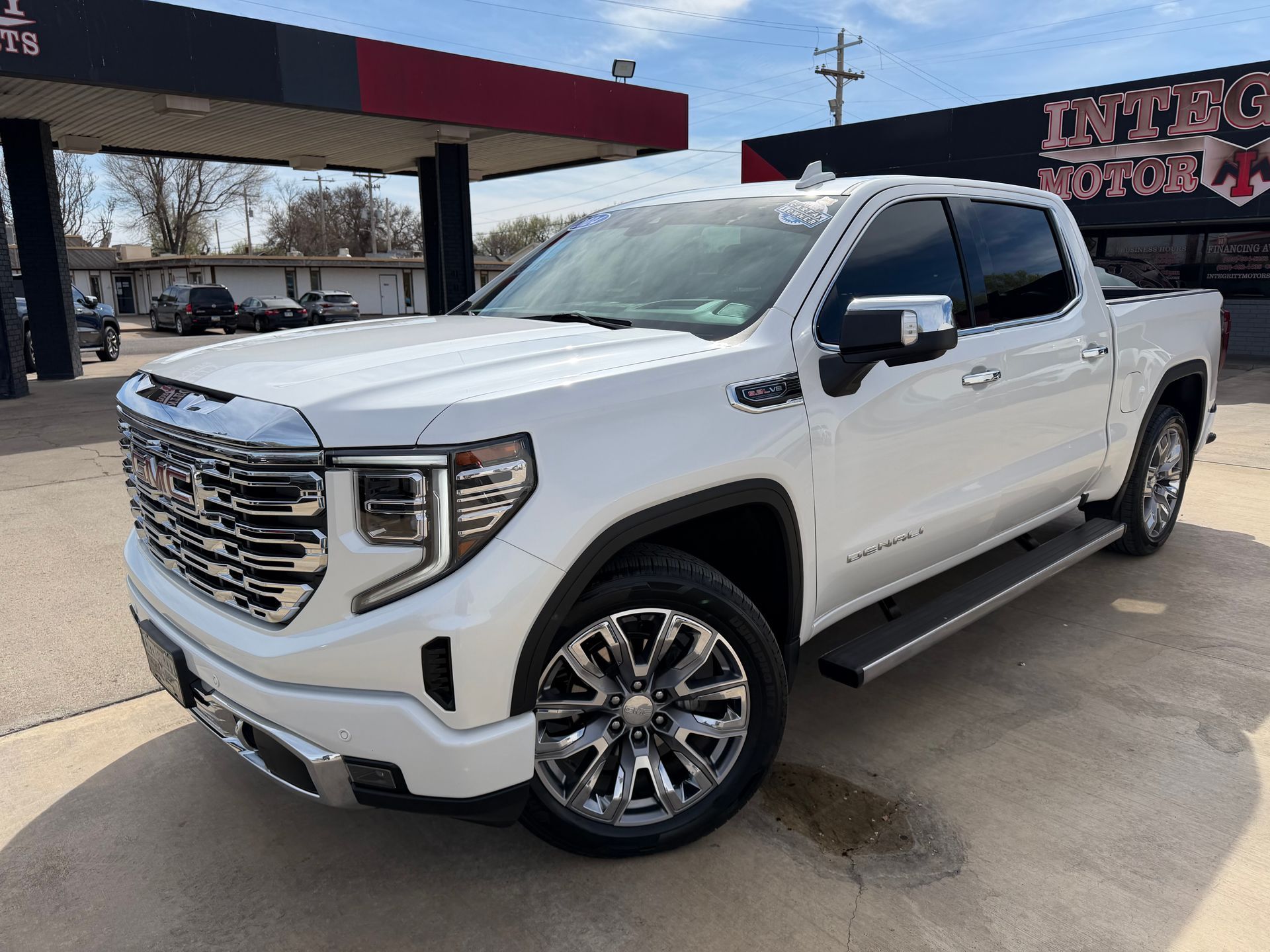 Black Chevrolet Silverado truck in front of a dealership with chrome accents and bright headlights.