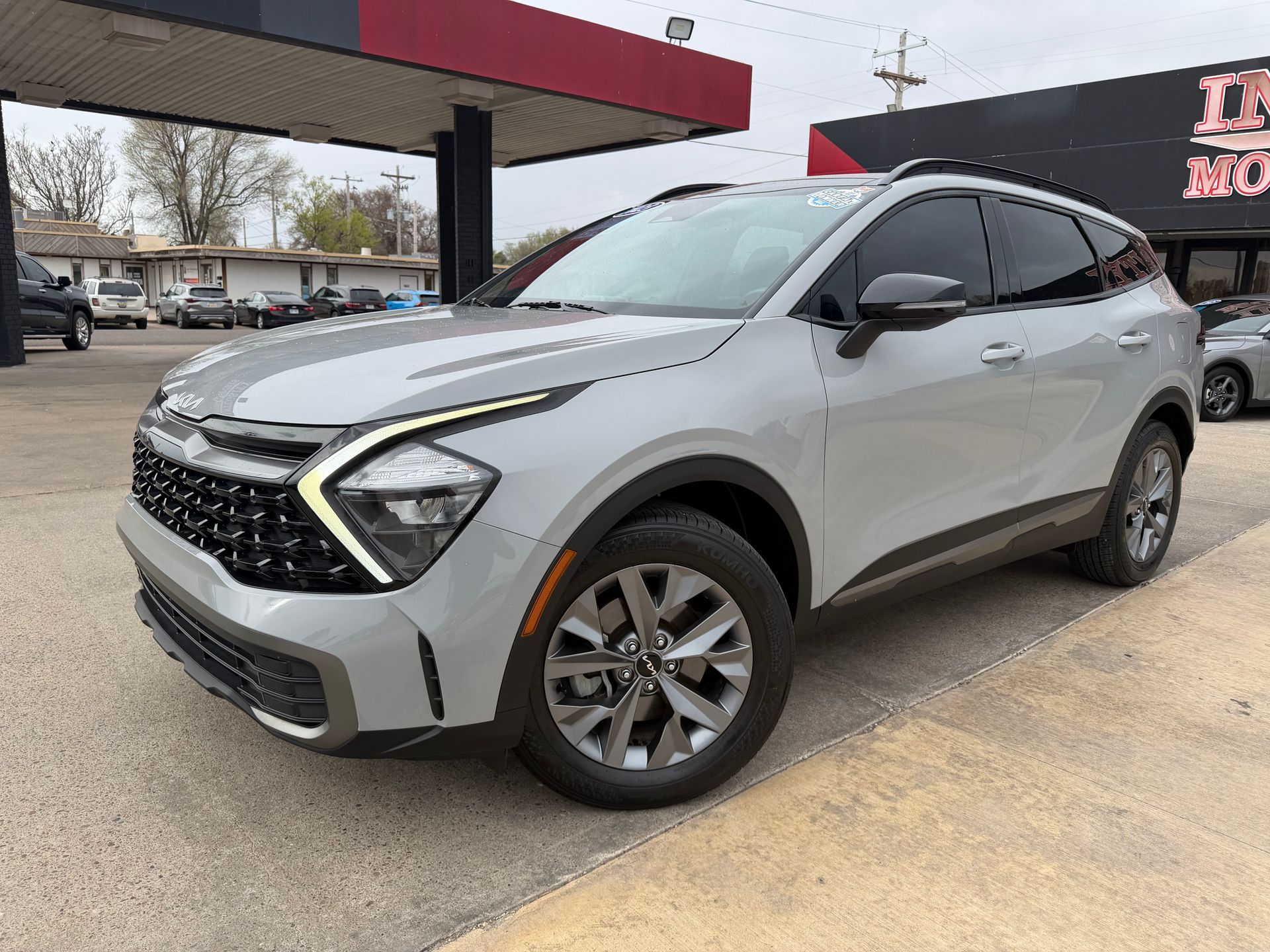 Black Jeep Grand Cherokee parked in front of a car dealership, front view.