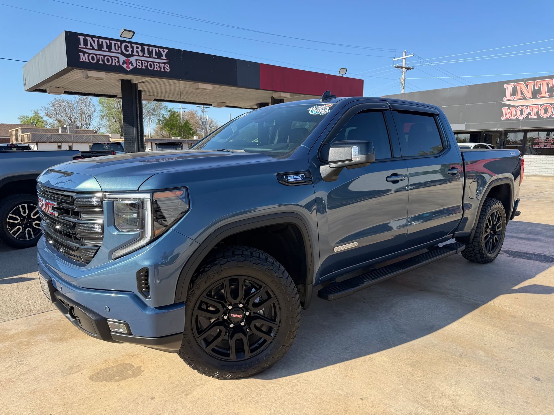 Black Chevrolet Silverado truck in front of a dealership with chrome accents and bright headlights.