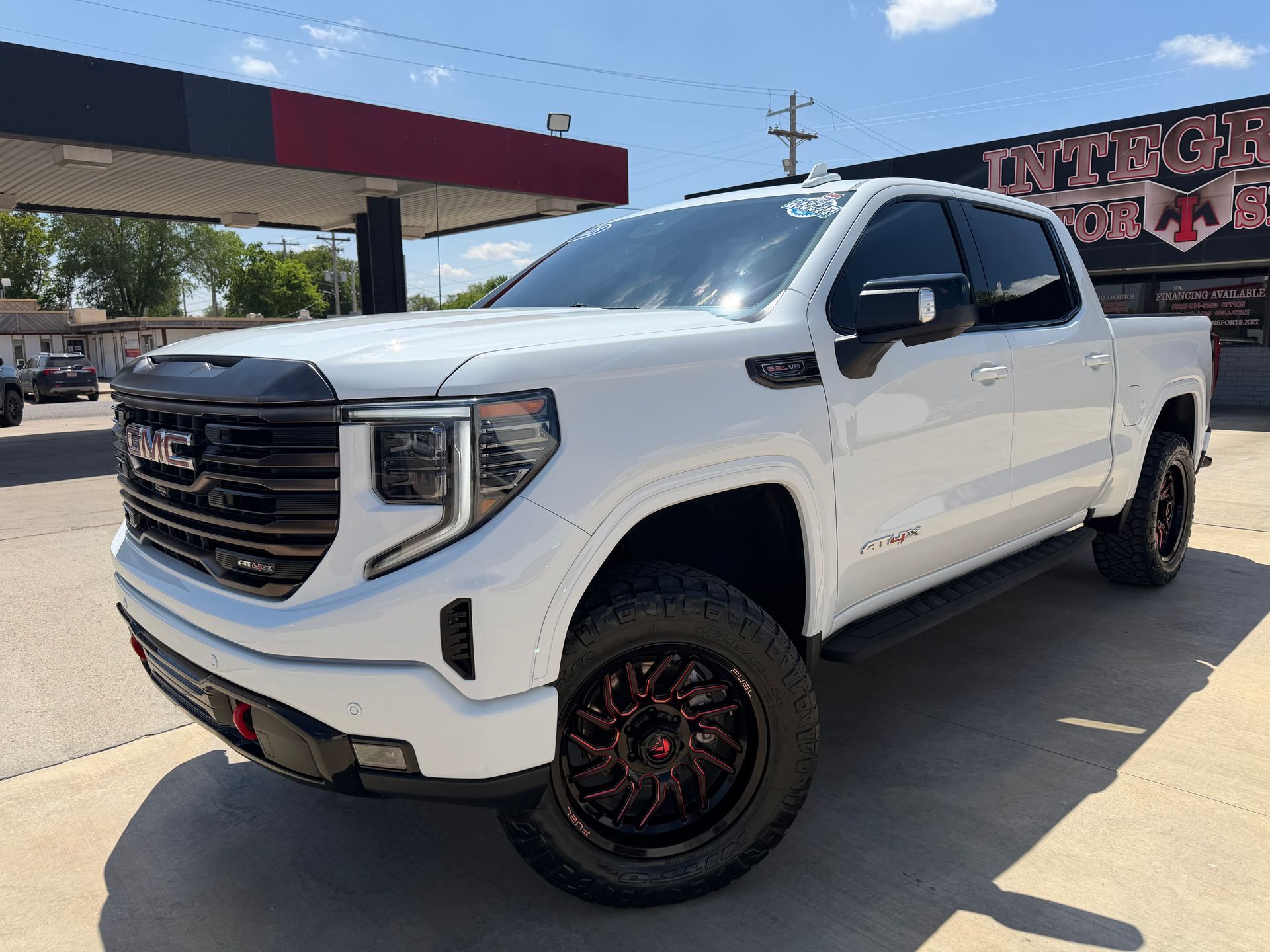 Black Chevrolet Silverado truck in front of a dealership with chrome accents and bright headlights.