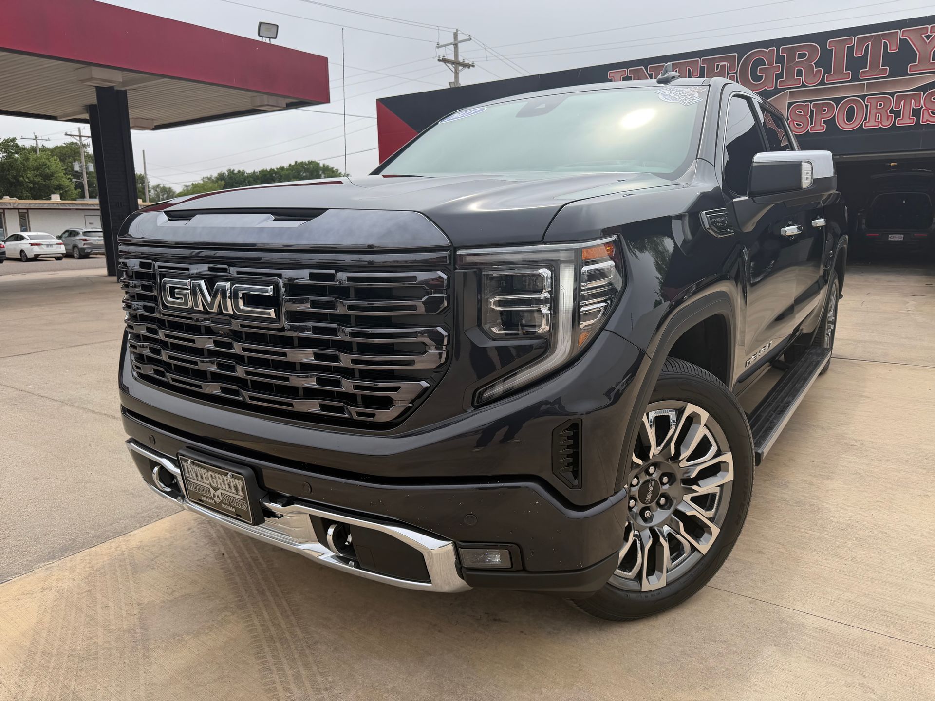 Black Chevrolet Silverado truck in front of a dealership with chrome accents and bright headlights.