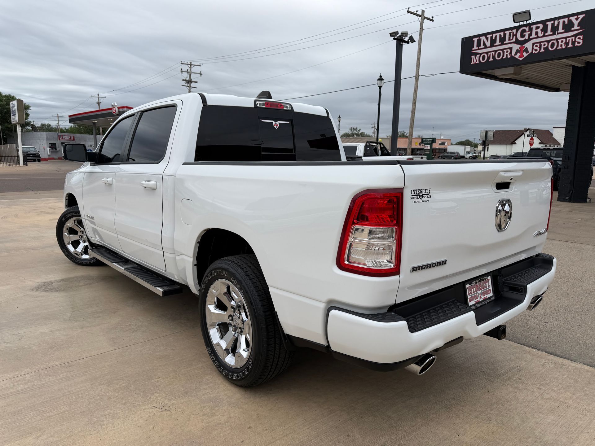 White RAM pickup truck parked outdoors near a motor sports dealership sign.