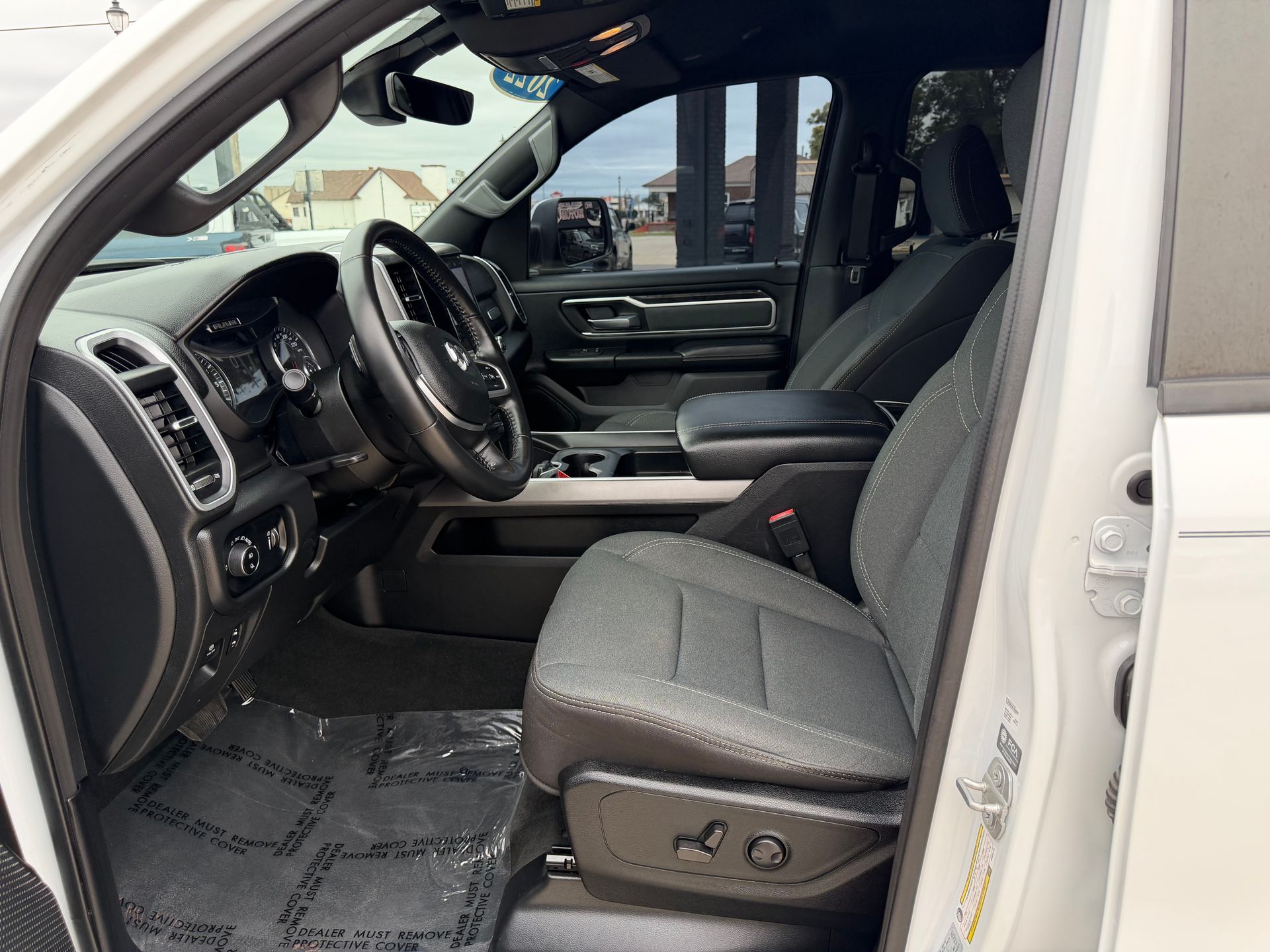 Truck interior with gray cloth seats, black dashboard, and open driver’s door