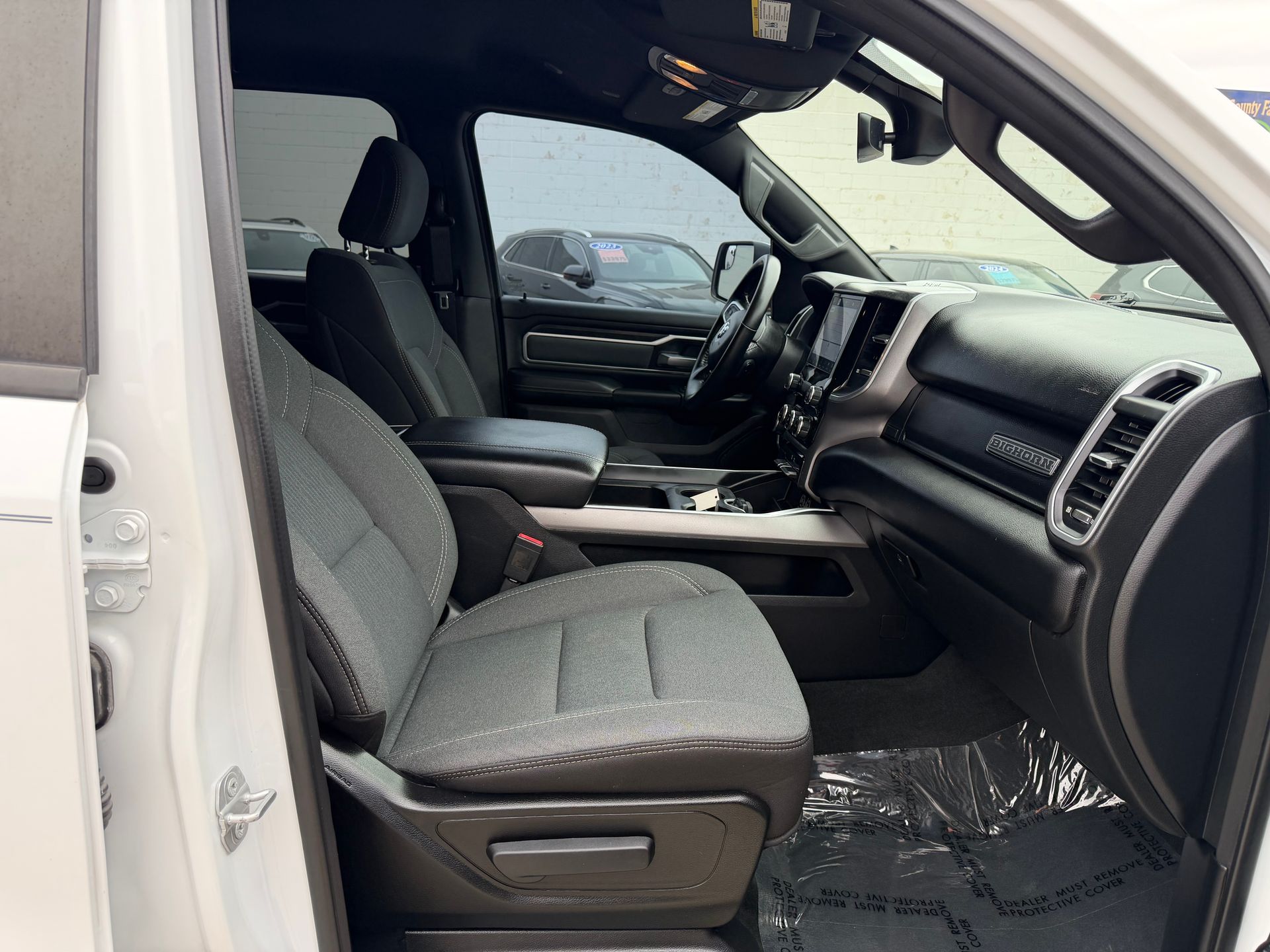Truck interior with gray front seats, dashboard, and open passenger door