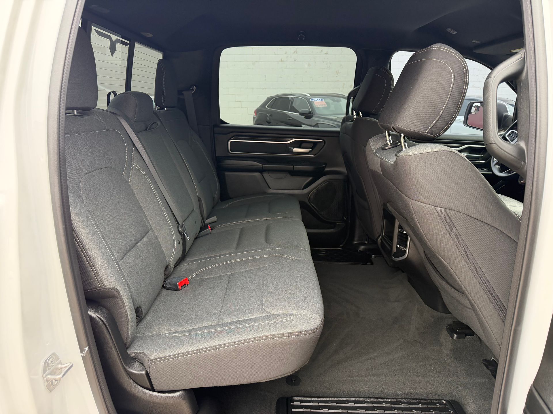 Car interior with gray cloth rear seats and front passenger seat visible, viewed through an open door