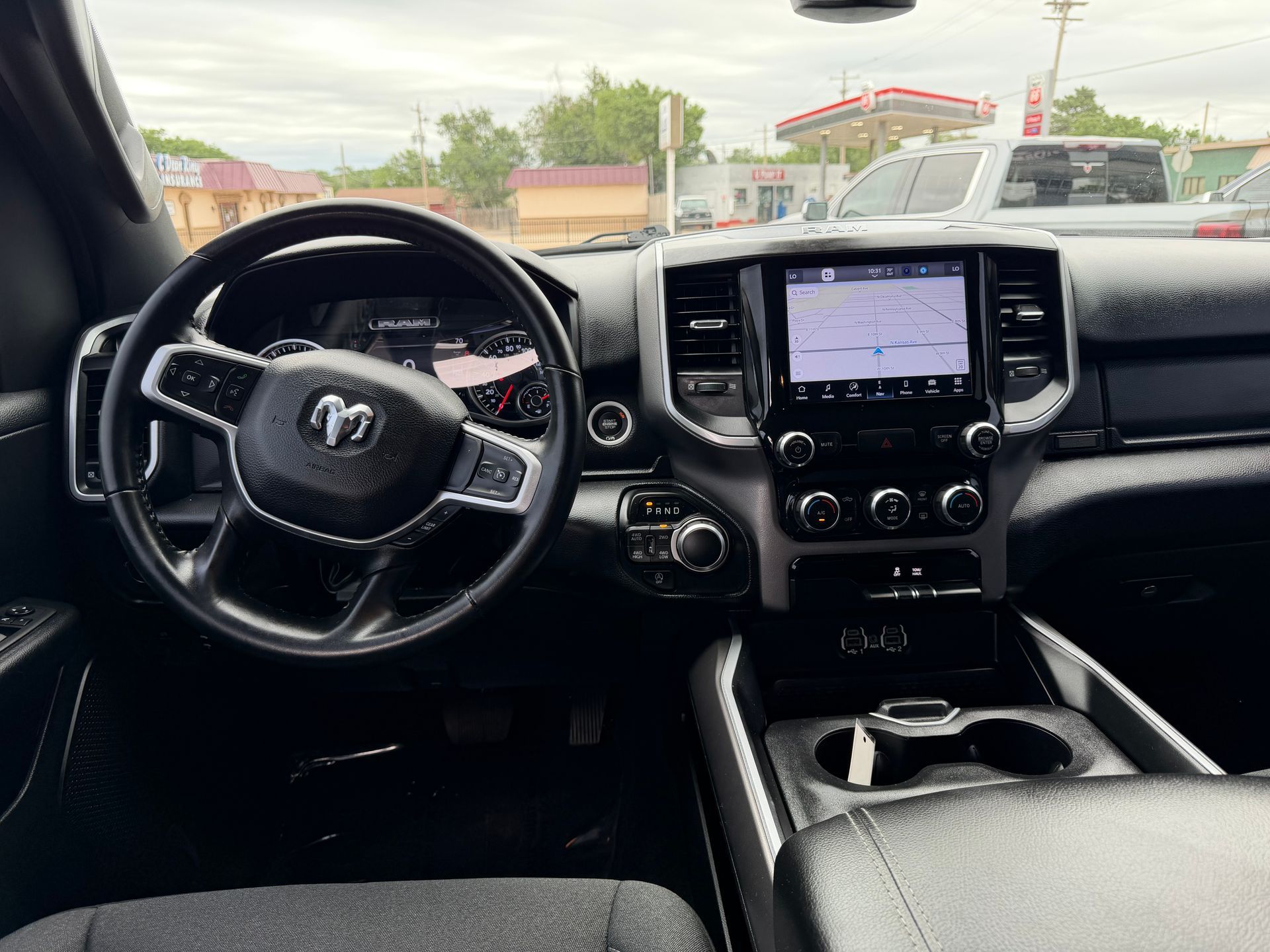 Car interior with steering wheel, dashboard touchscreen, and center console, viewed from the front seats.
