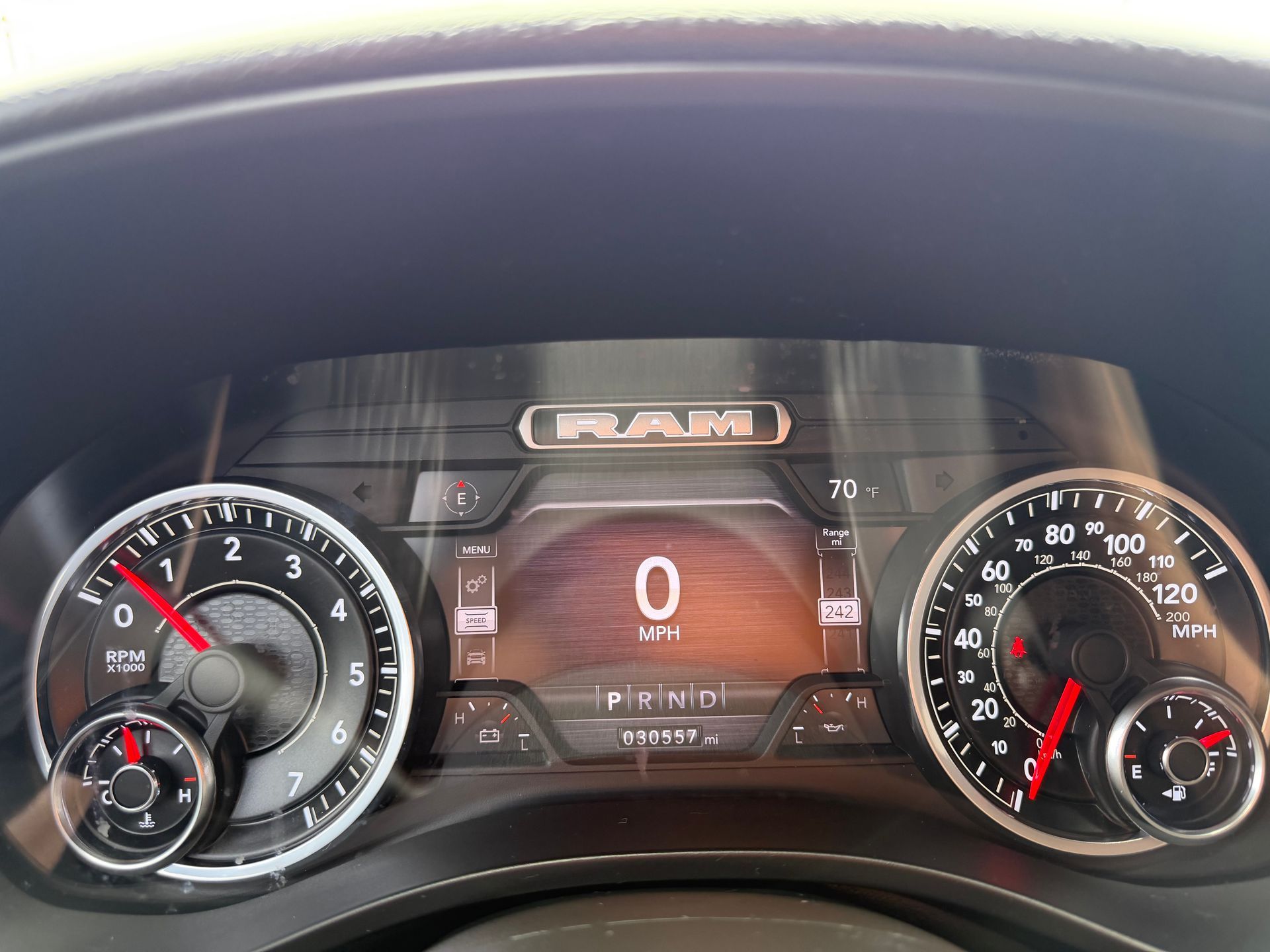 Car dashboard with analog gauges and digital speed display reading 0 mph