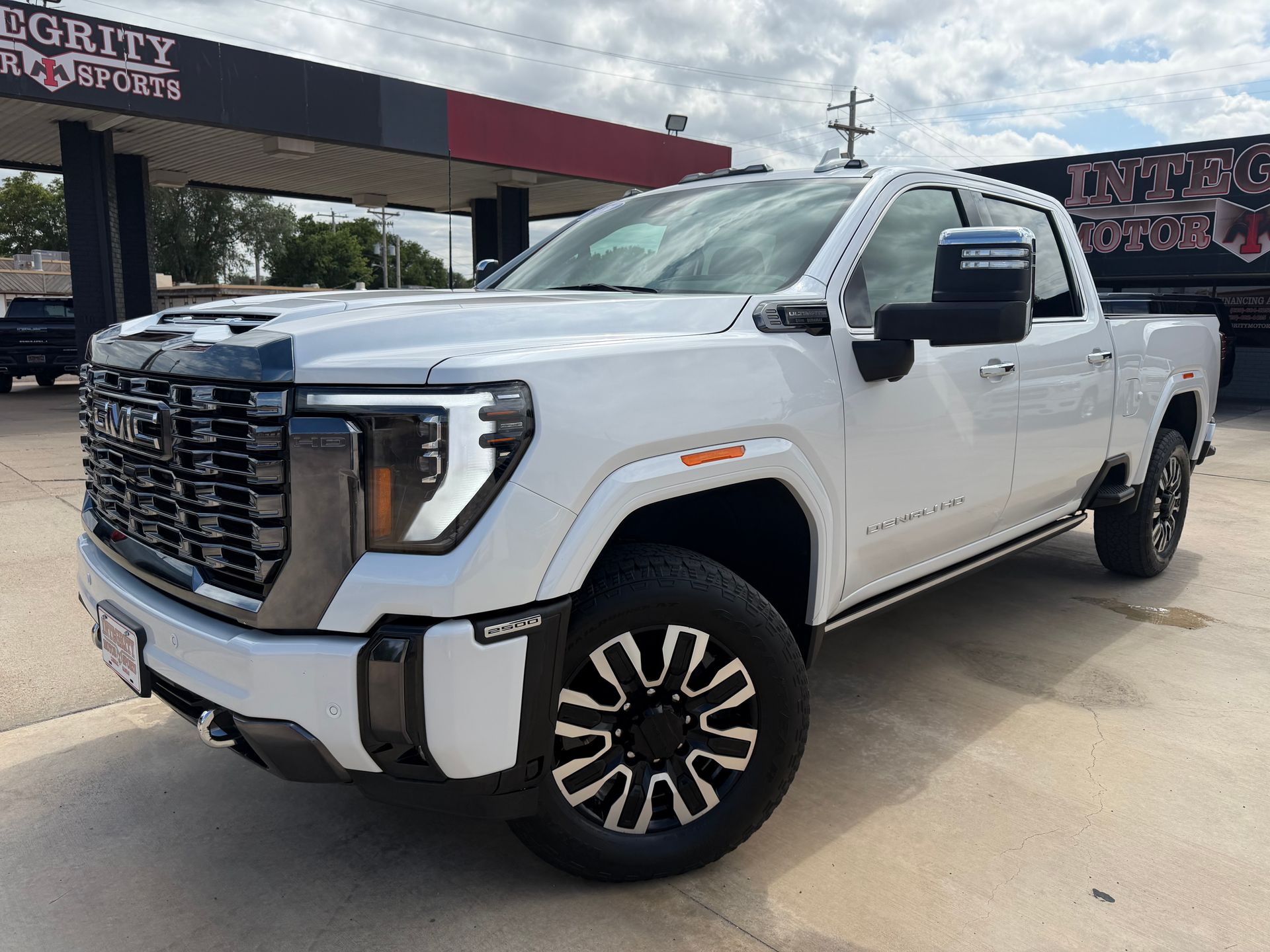 Black Chevrolet Silverado truck in front of a dealership with chrome accents and bright headlights.