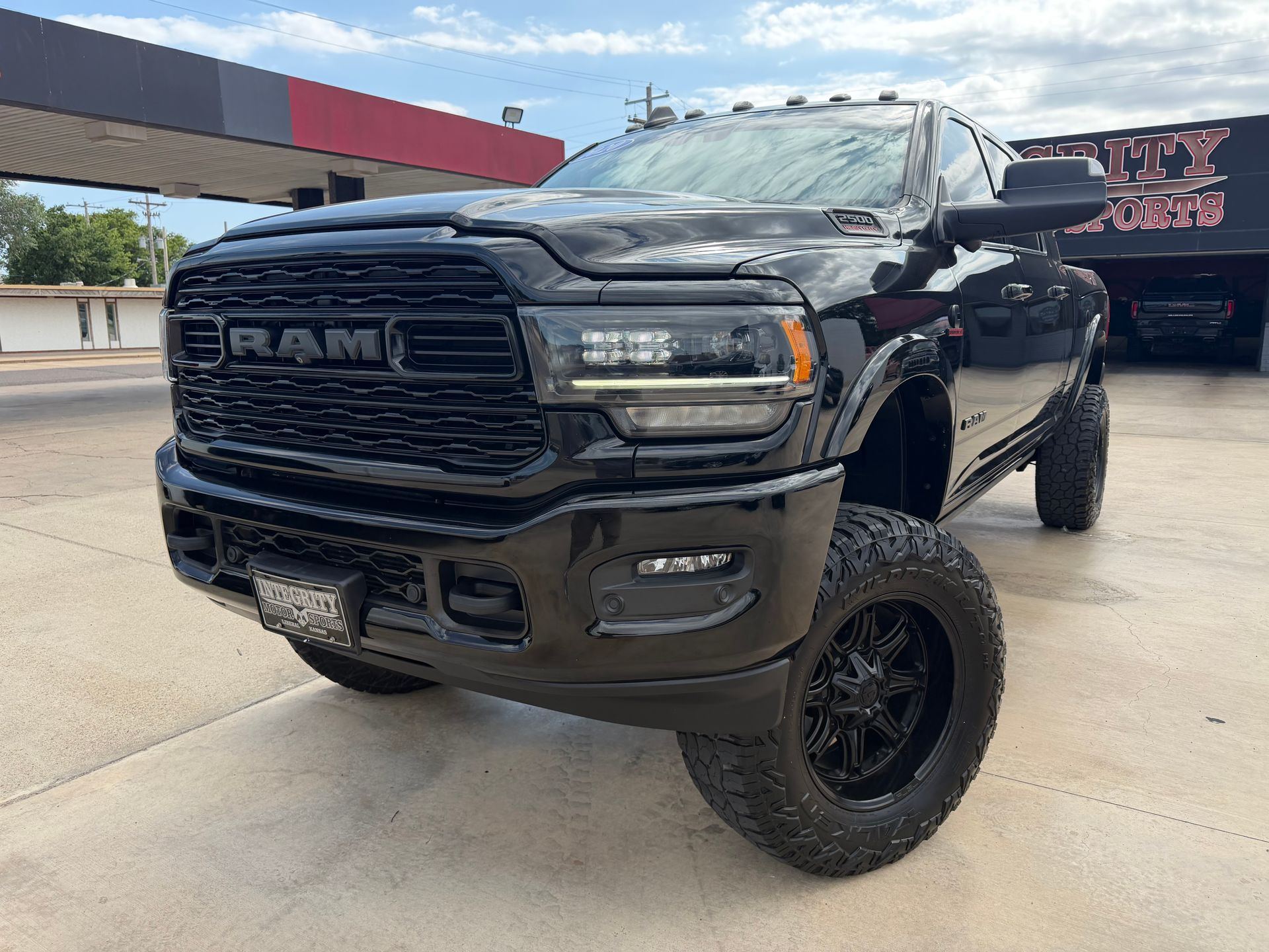 Black Chevrolet Silverado truck in front of a dealership with chrome accents and bright headlights.