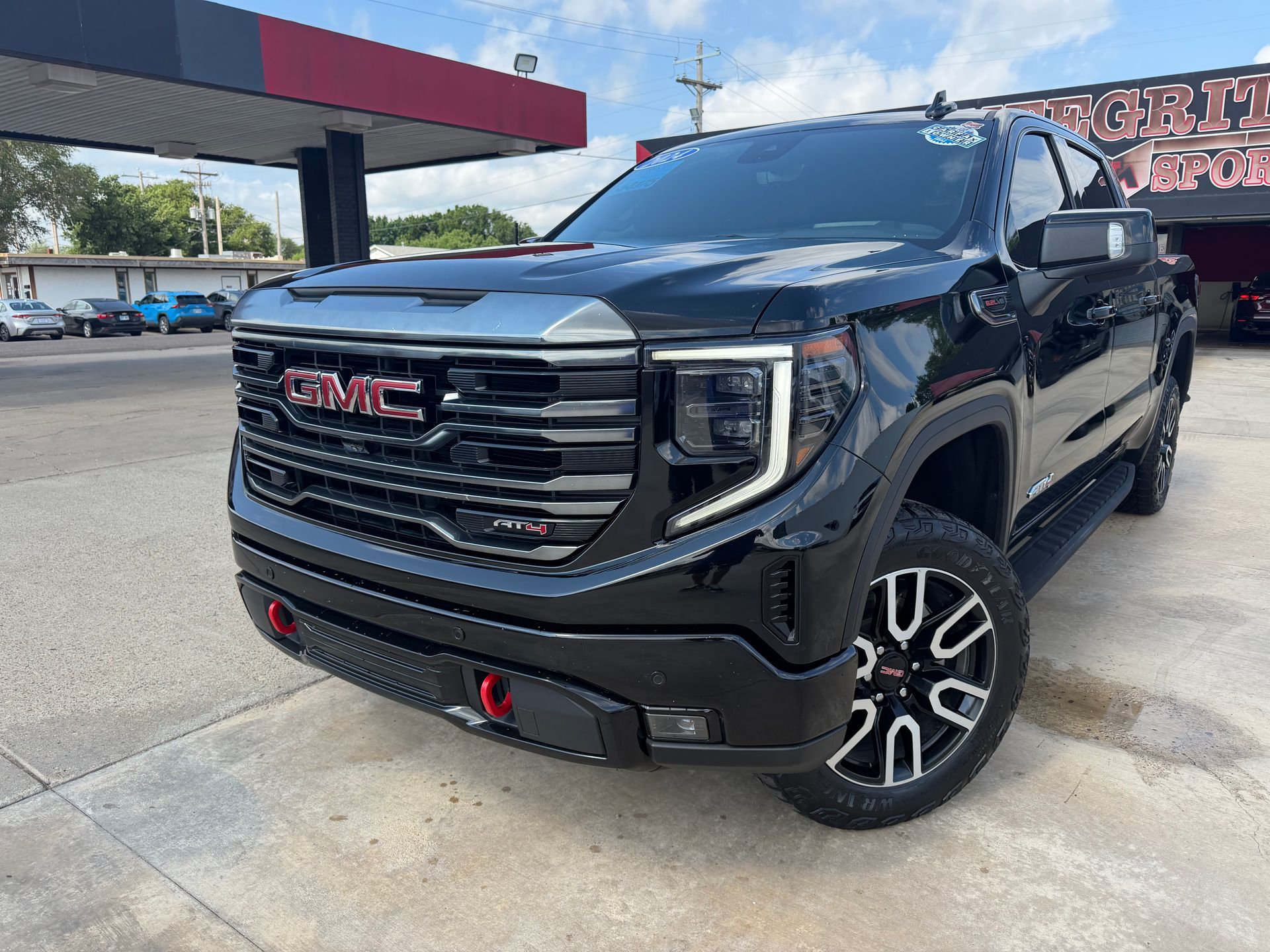 Black Chevrolet Silverado truck in front of a dealership with chrome accents and bright headlights.