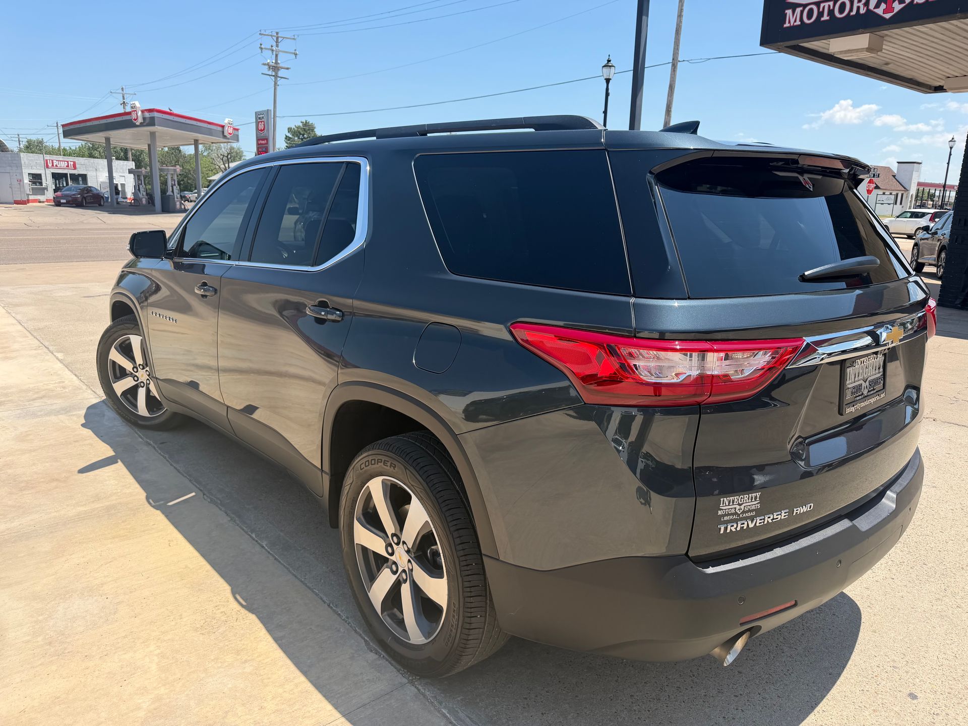 Black SUV parked at a gas station under a bright sky