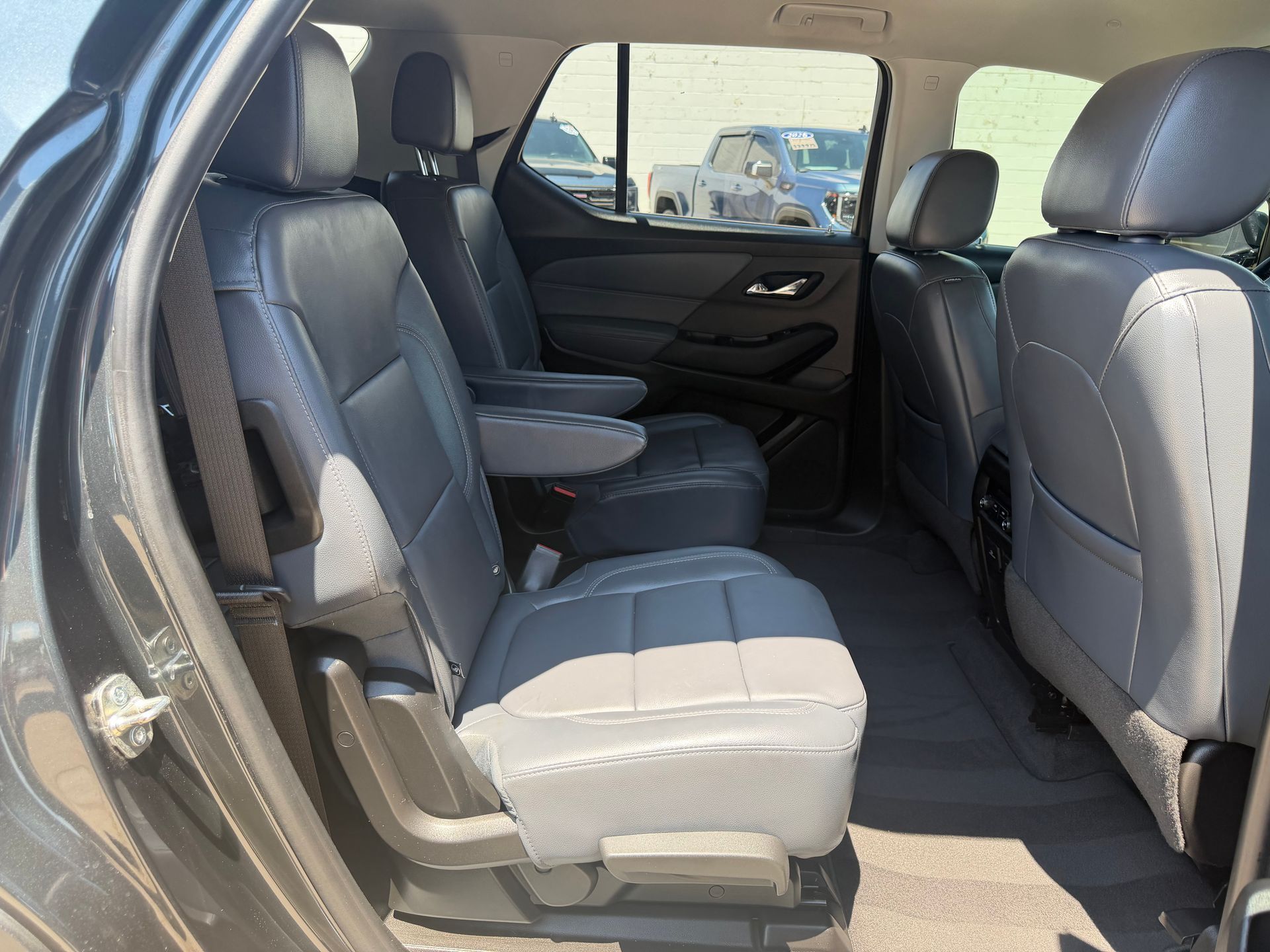 Inside a car, gray cloth rear seats with the doors open, showing the back seat area.