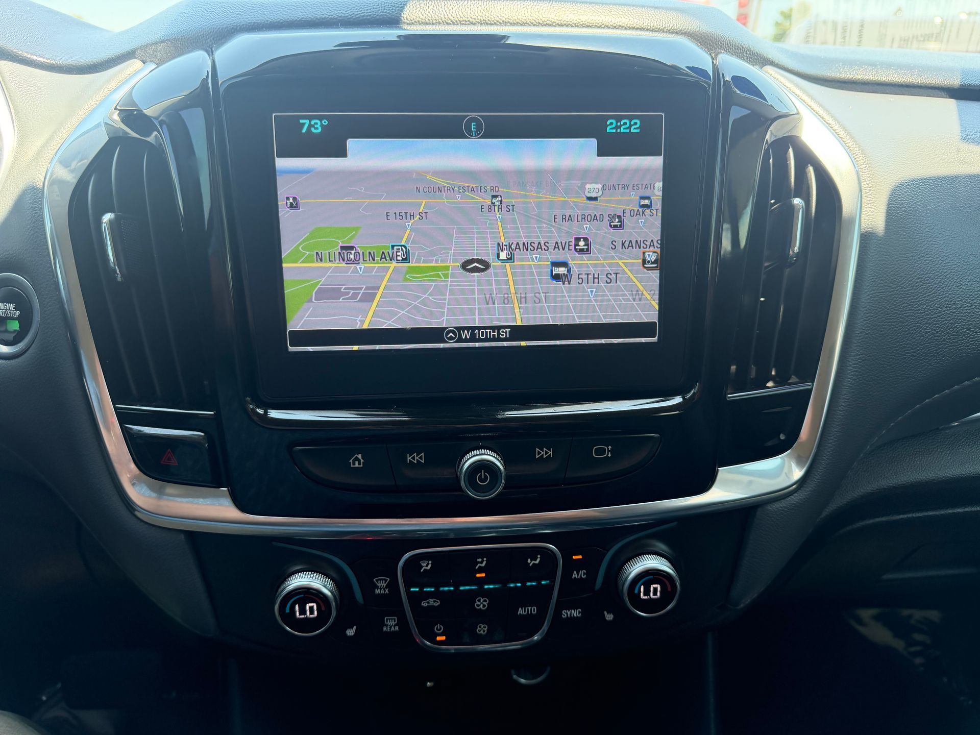 Car dashboard with center touchscreen showing a GPS navigation map and climate controls below.