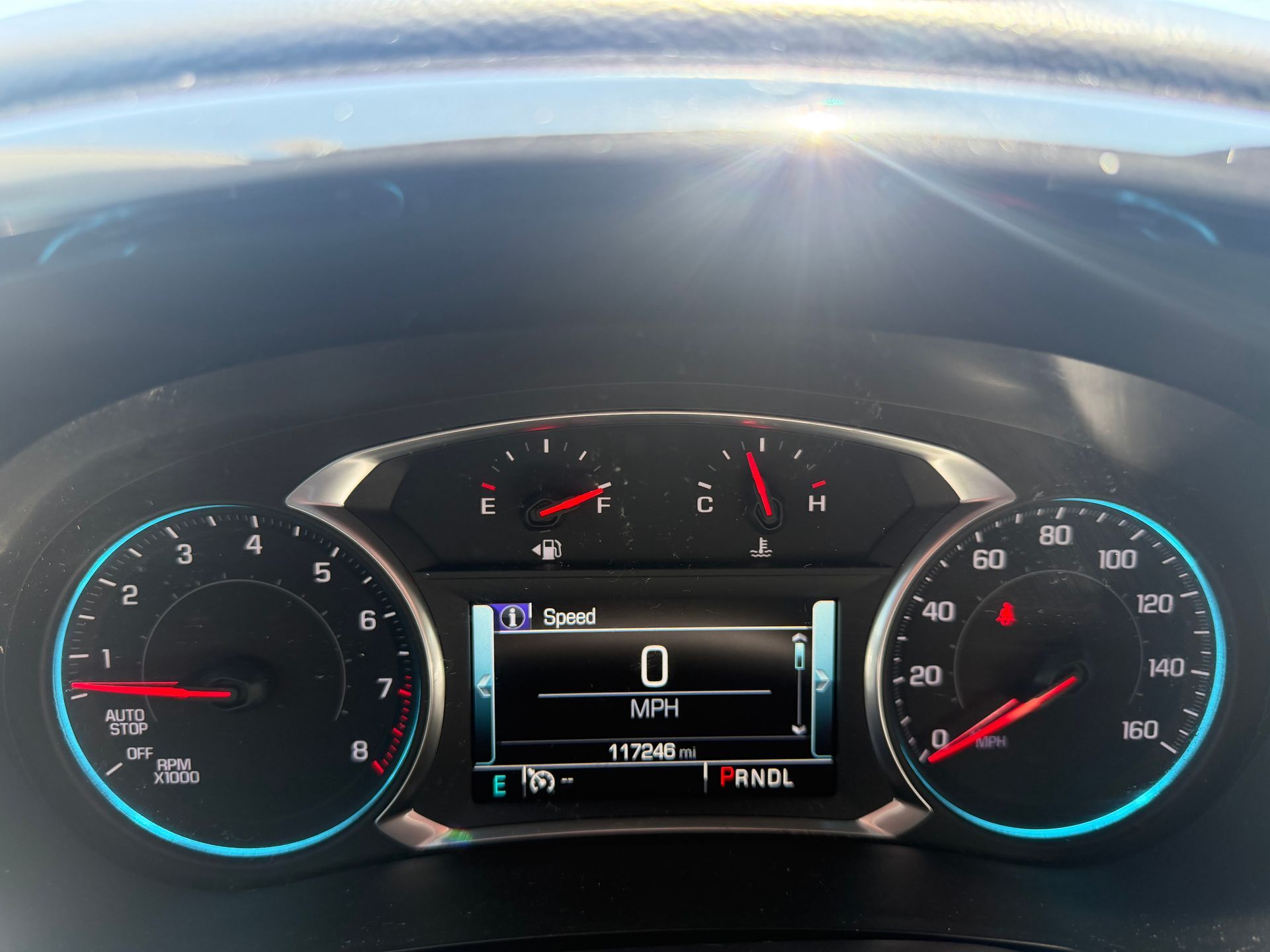 Car dashboard with digital speedometer at 0 mph and fuel gauge near full.