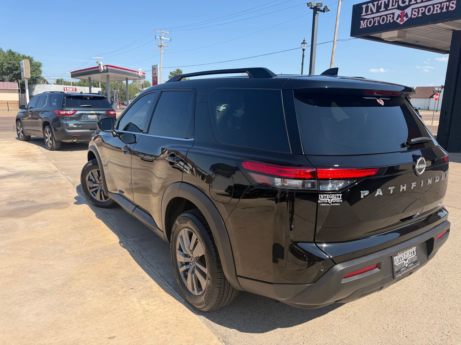 Black Nissan Pathfinder SUV parked on a sunny car lot, rear three-quarter view