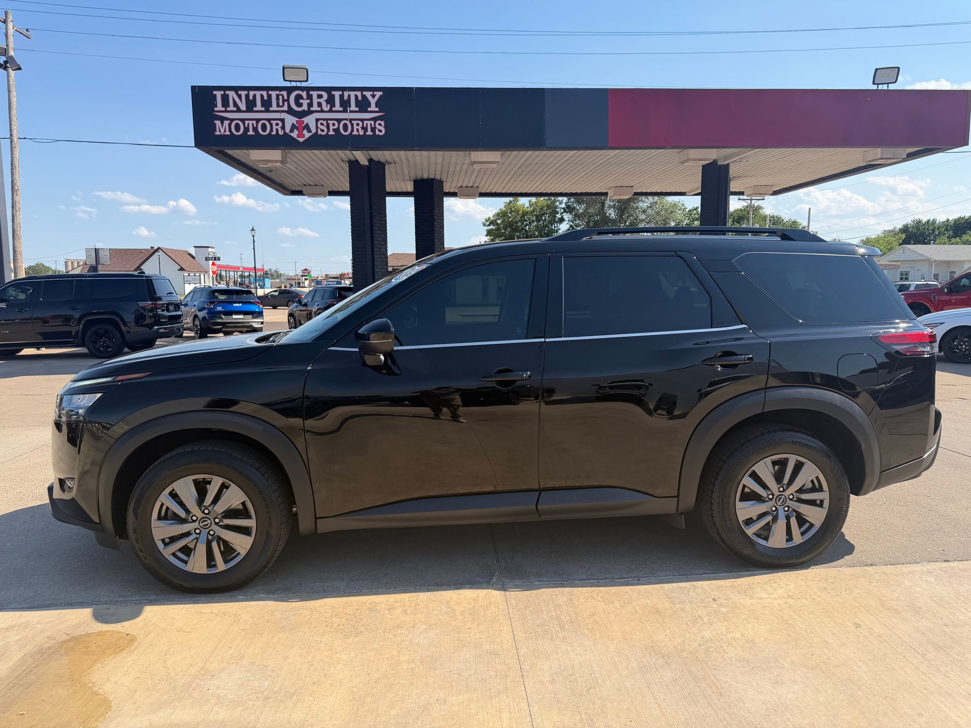 Black SUV parked in front of an Integrity Motors sign on a sunny day