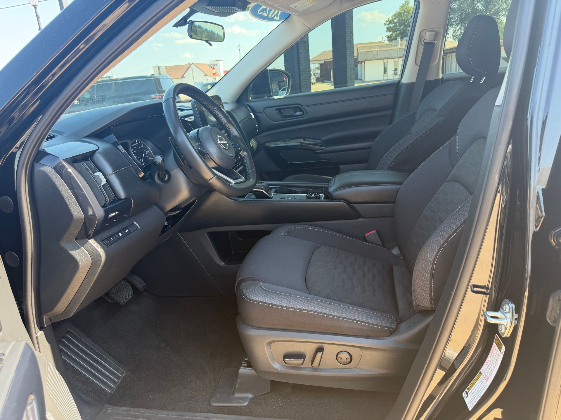 Black pickup truck interior with open driver door, gray cloth seats, and steering wheel visible