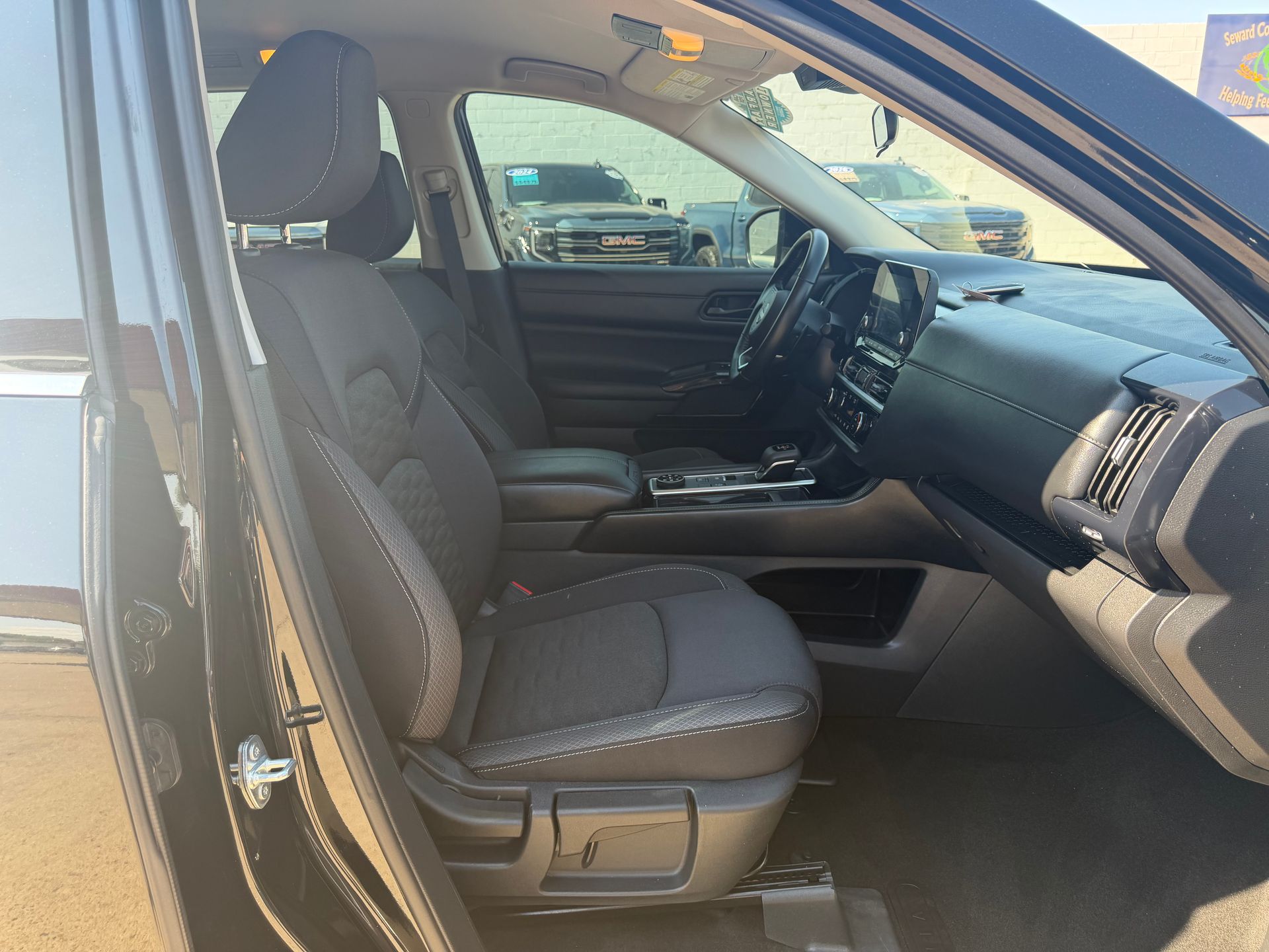 Front passenger seat of a black truck with the door open, showing a gray cloth interior and dashboard.