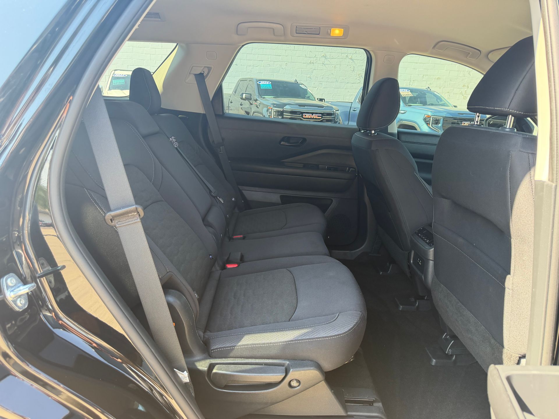 Car interior with rear bench seat in gray upholstery, viewed from the open rear door.
