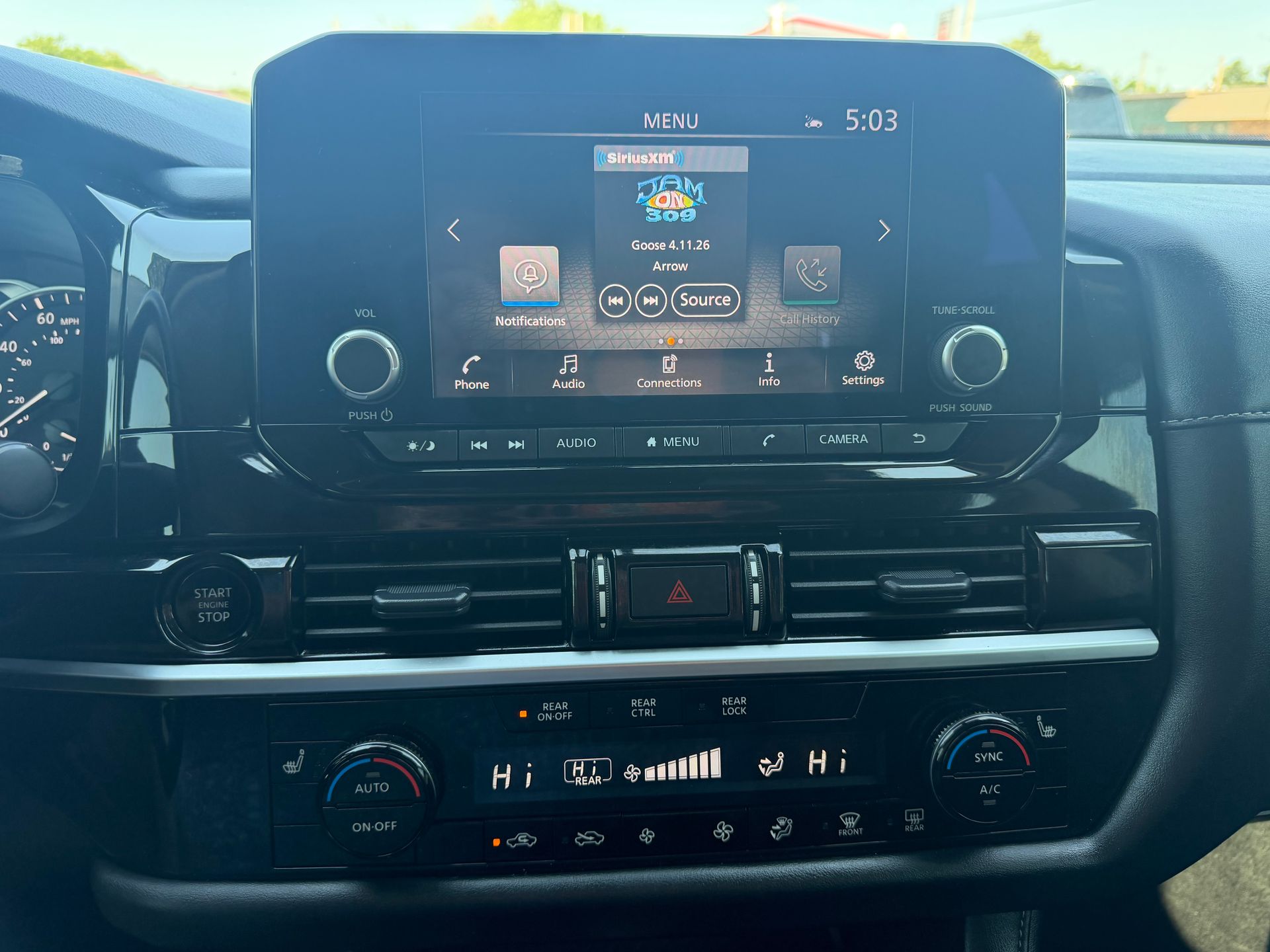 Car dashboard with central infotainment screen, air vents, and climate controls in a parked vehicle.